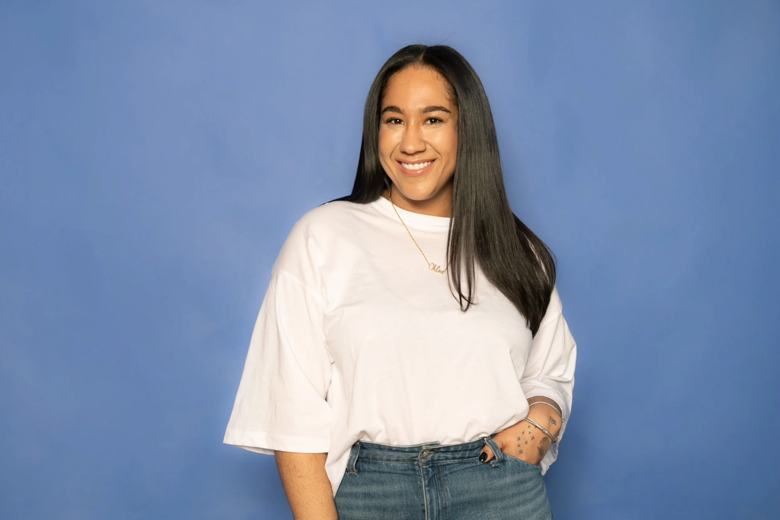 Founder Chloe Johnston smiling and standing against a blue background.