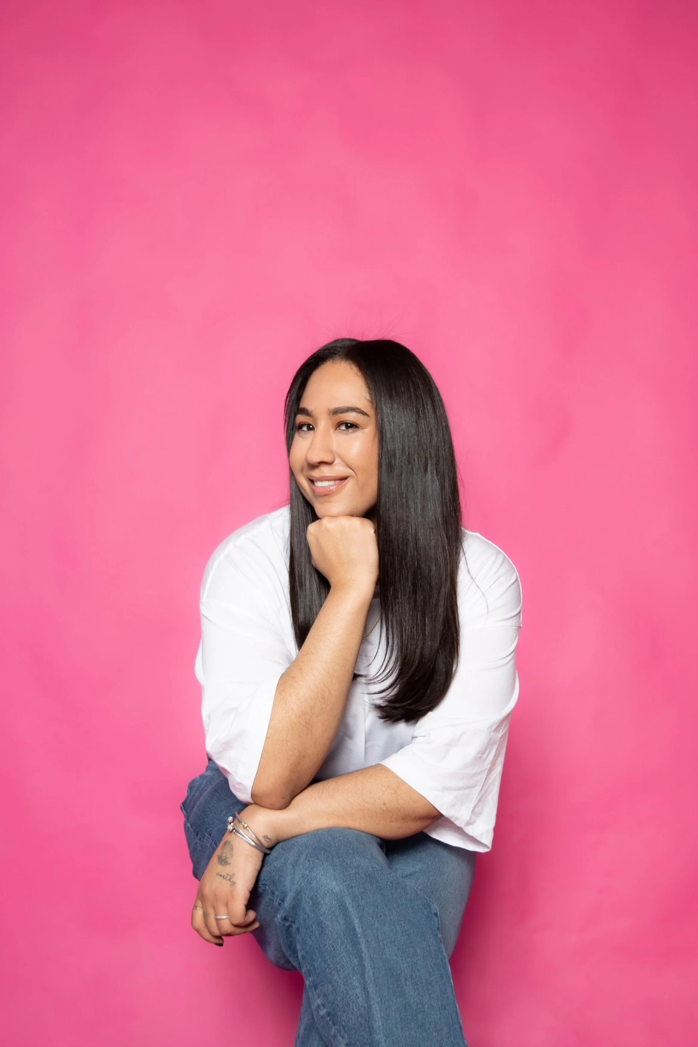 Founder Chloe Johnston sitting against a pink background, smiling.