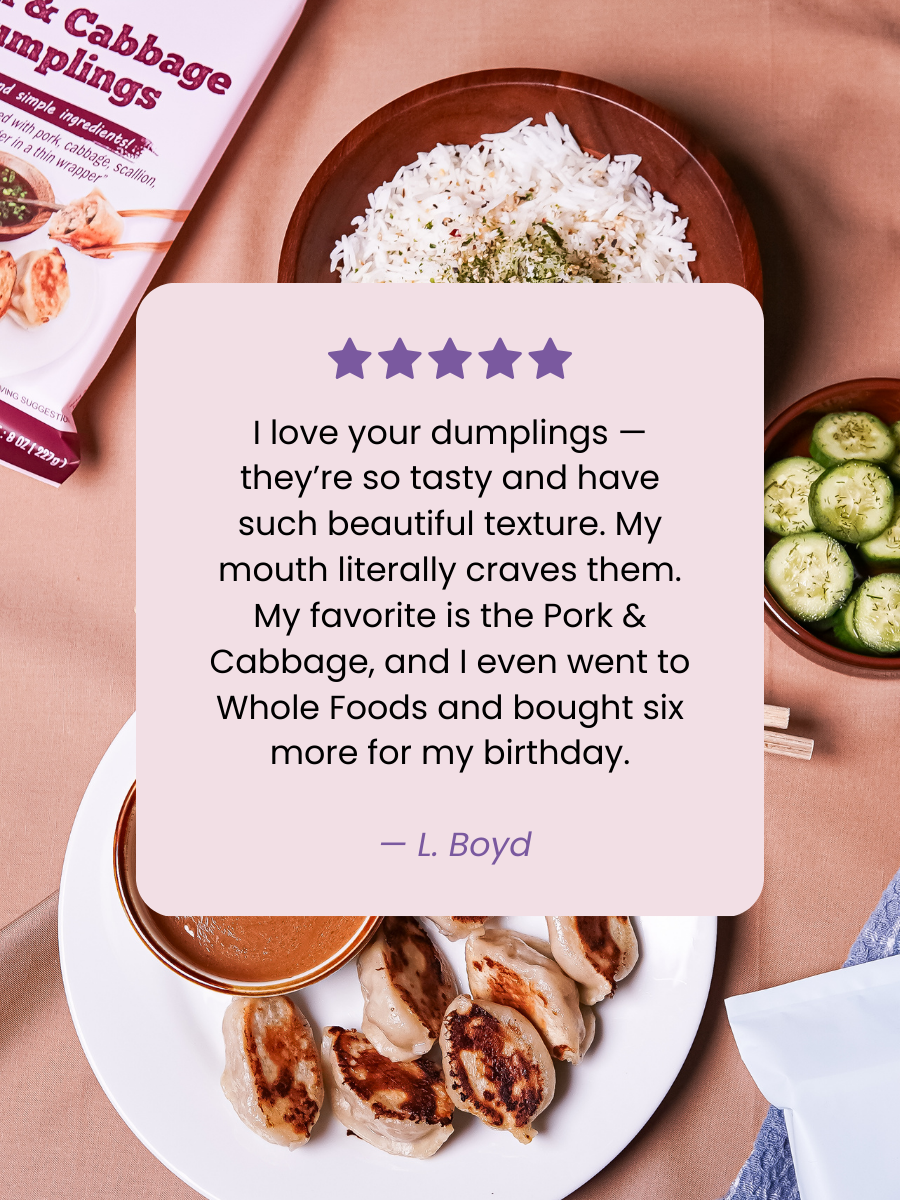 A bowl of white rice with herbs, sliced cucumbers, and a plate of pan-fried dumplings with dipping sauce on a pink table. A food package labeled "Pork & Cabbage Dumplings" is visible at the top left.
