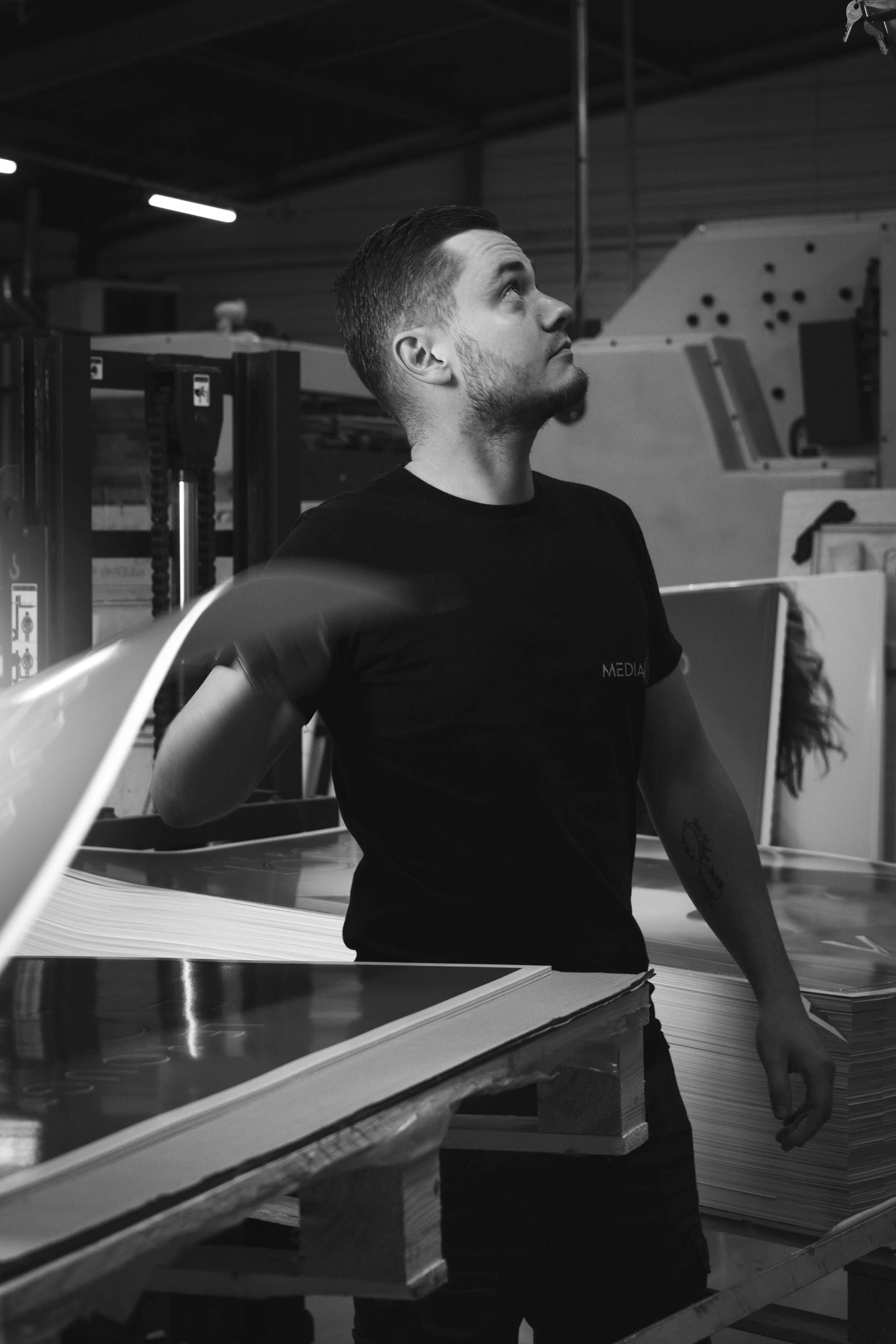 Un homme regardant vers le haut dans une usine ou un atelier, entouré de matériaux de fabrication.