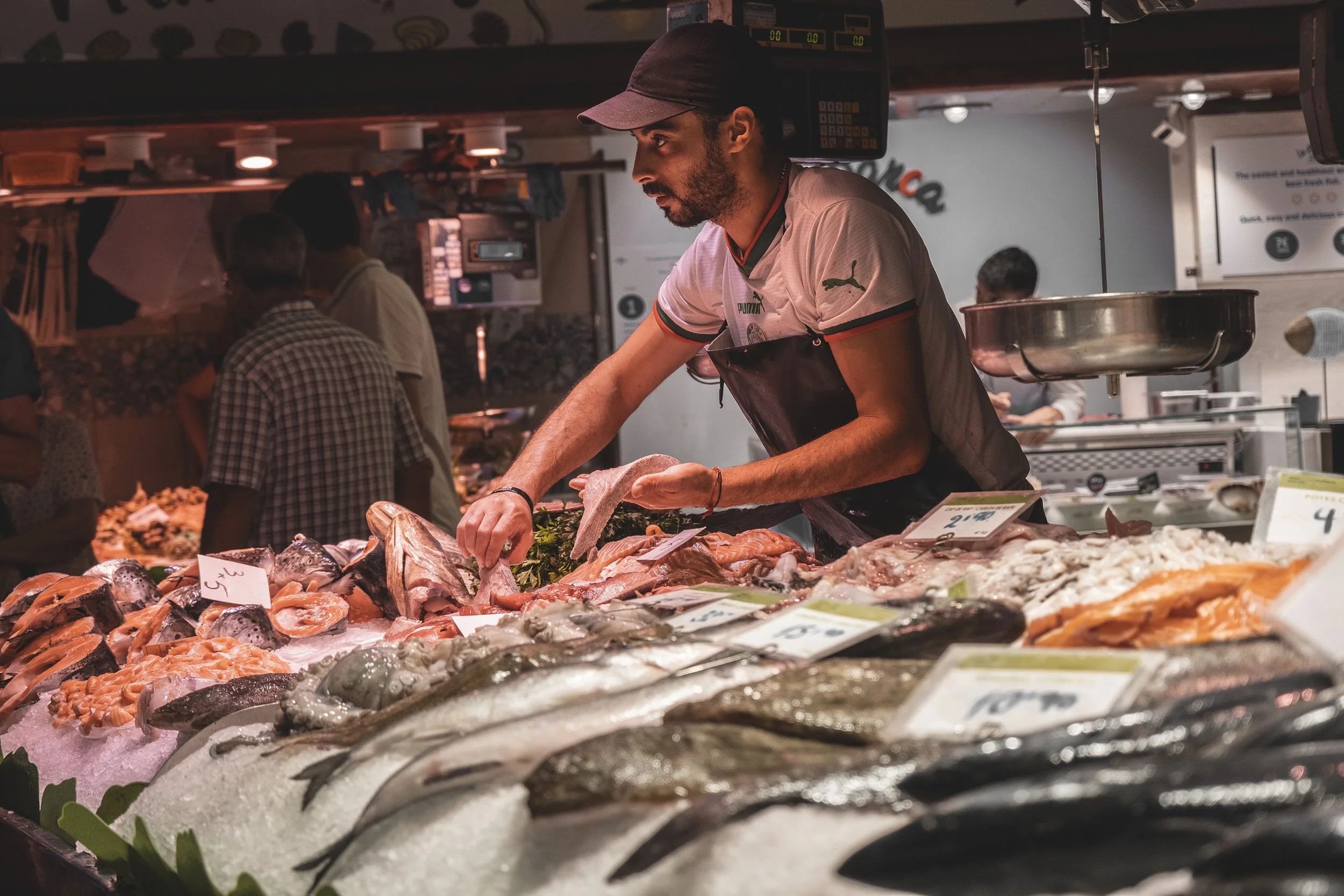 Un homme vendant du poisson frais dans un marché en intérieur.