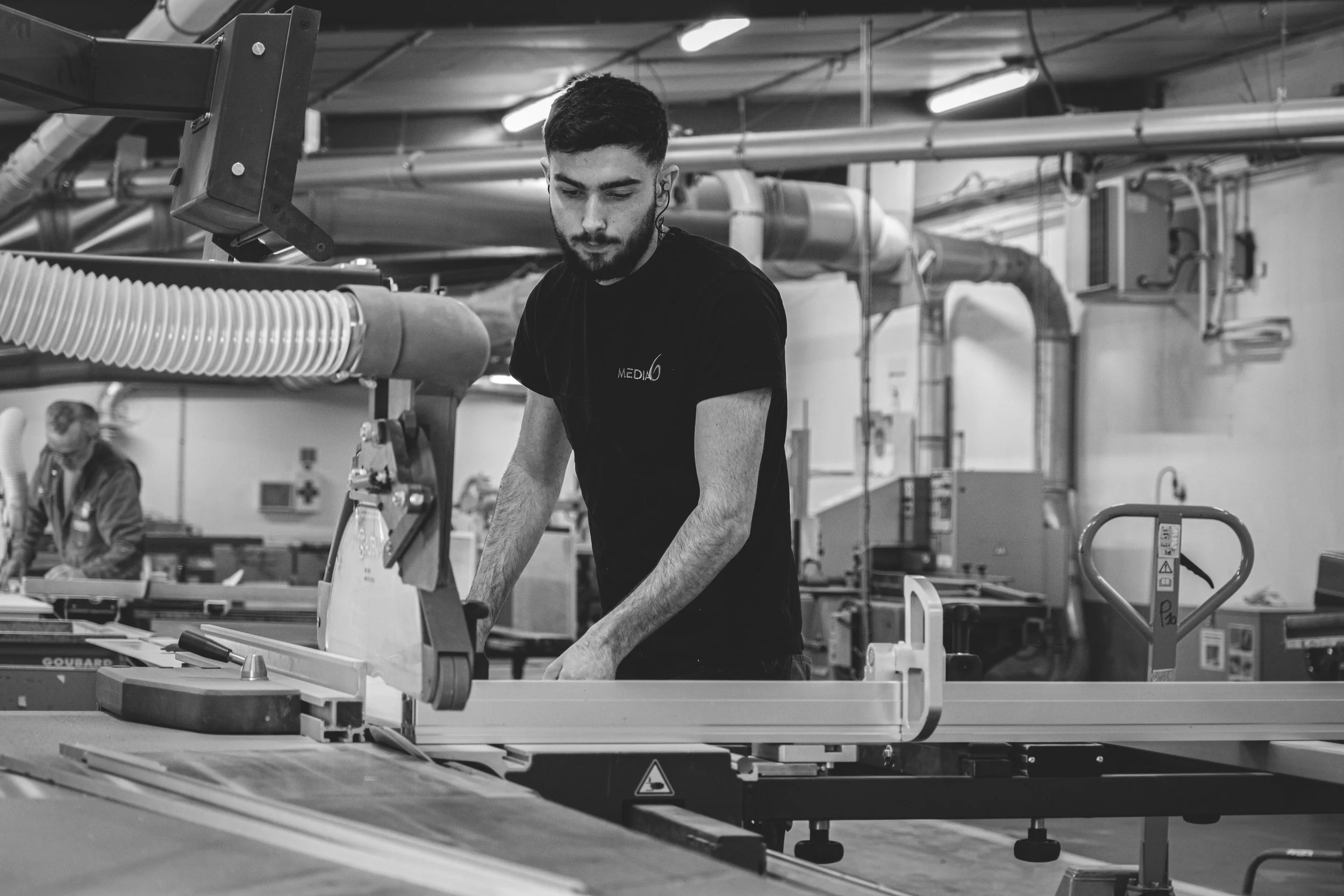 Un homme travaillant sur une machine dans une usine, en noir et blanc.