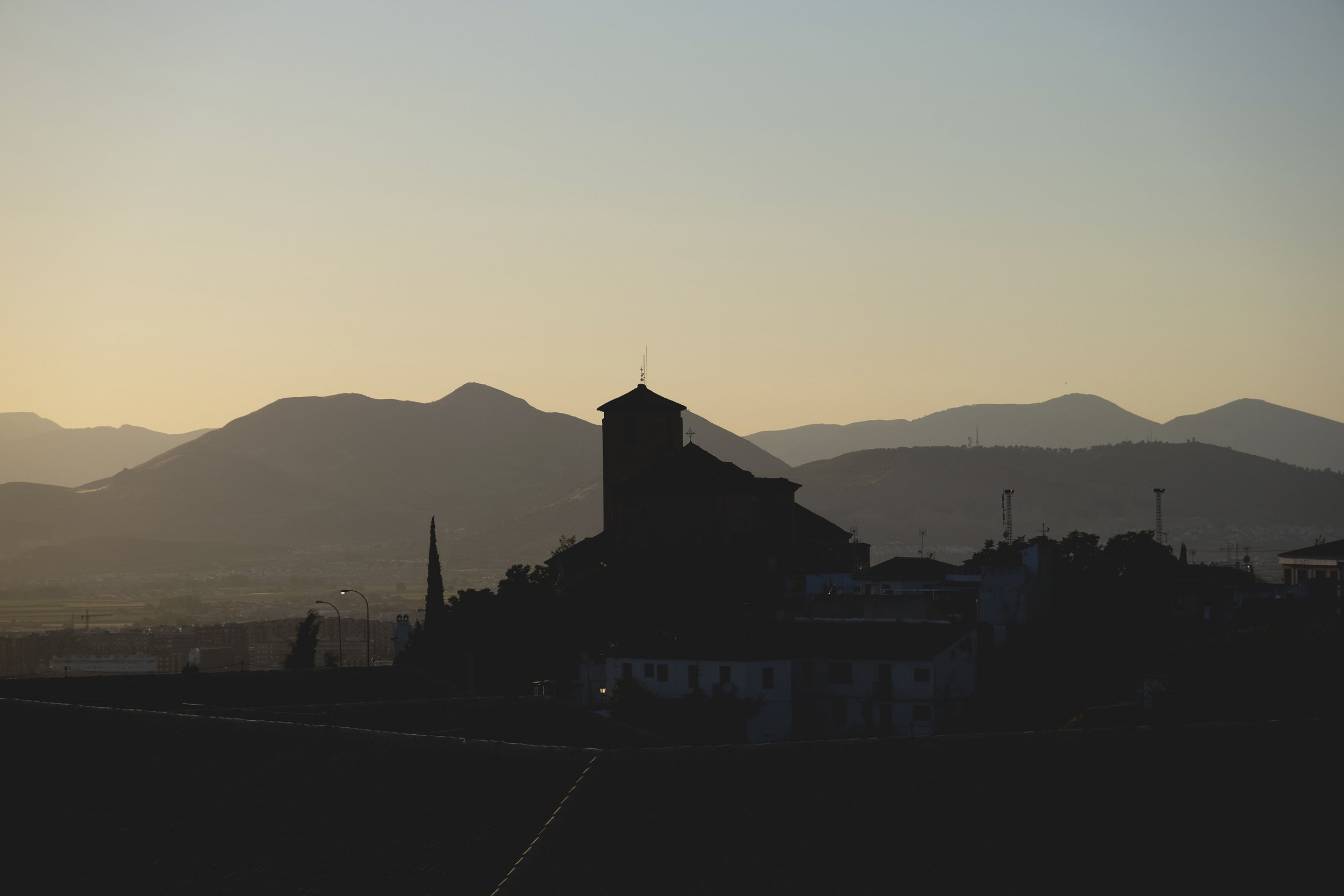 Silhouette d'une église avec des montagnes en arrière-plan au crépuscule.