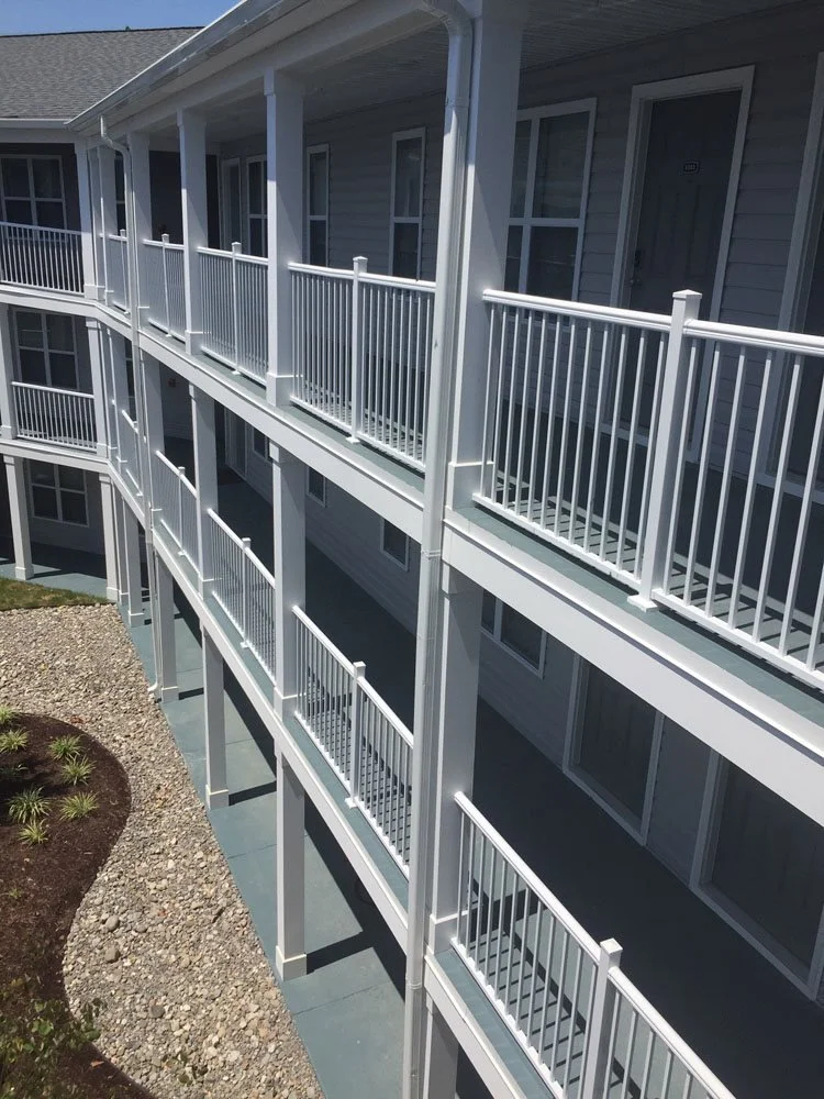 Exterior view of a multi-story residential building with white railing balconies on each floor.