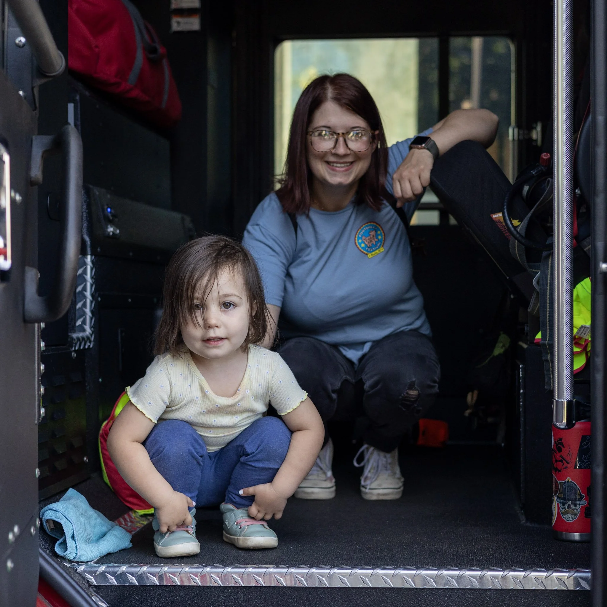 A woman and a young girl sitting inside a fire truck