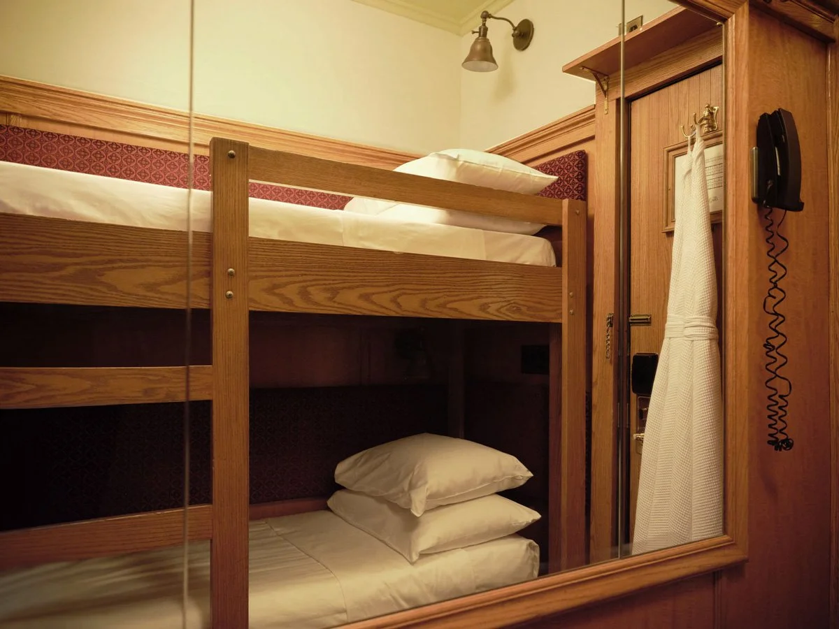 Room with bunk beds, a mirror, wall-mounted telephone, and wooden furniture.