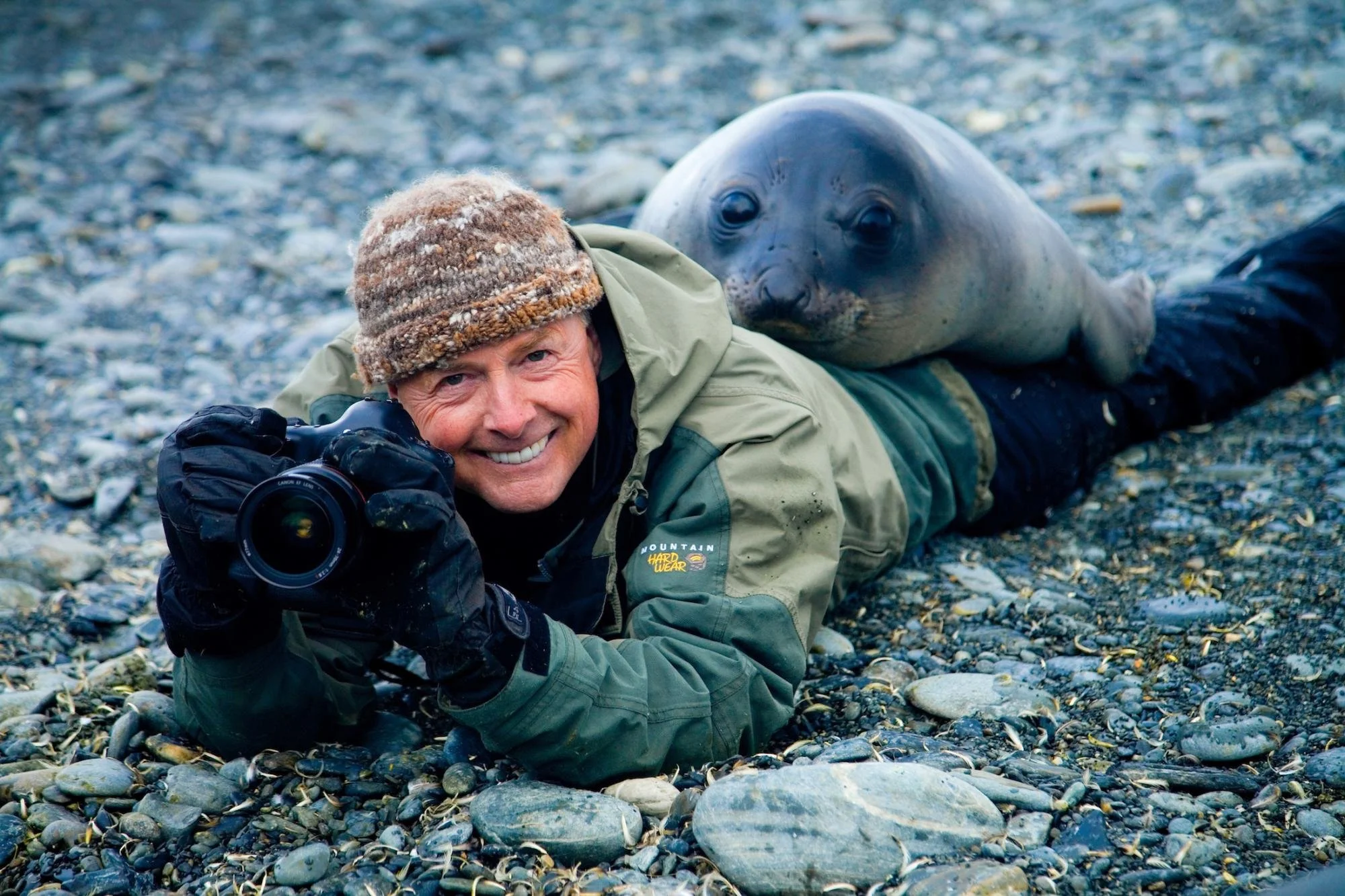 Portrait of photographer Art Wolfe holding a camera outdoors during a wildlife photography shoot.