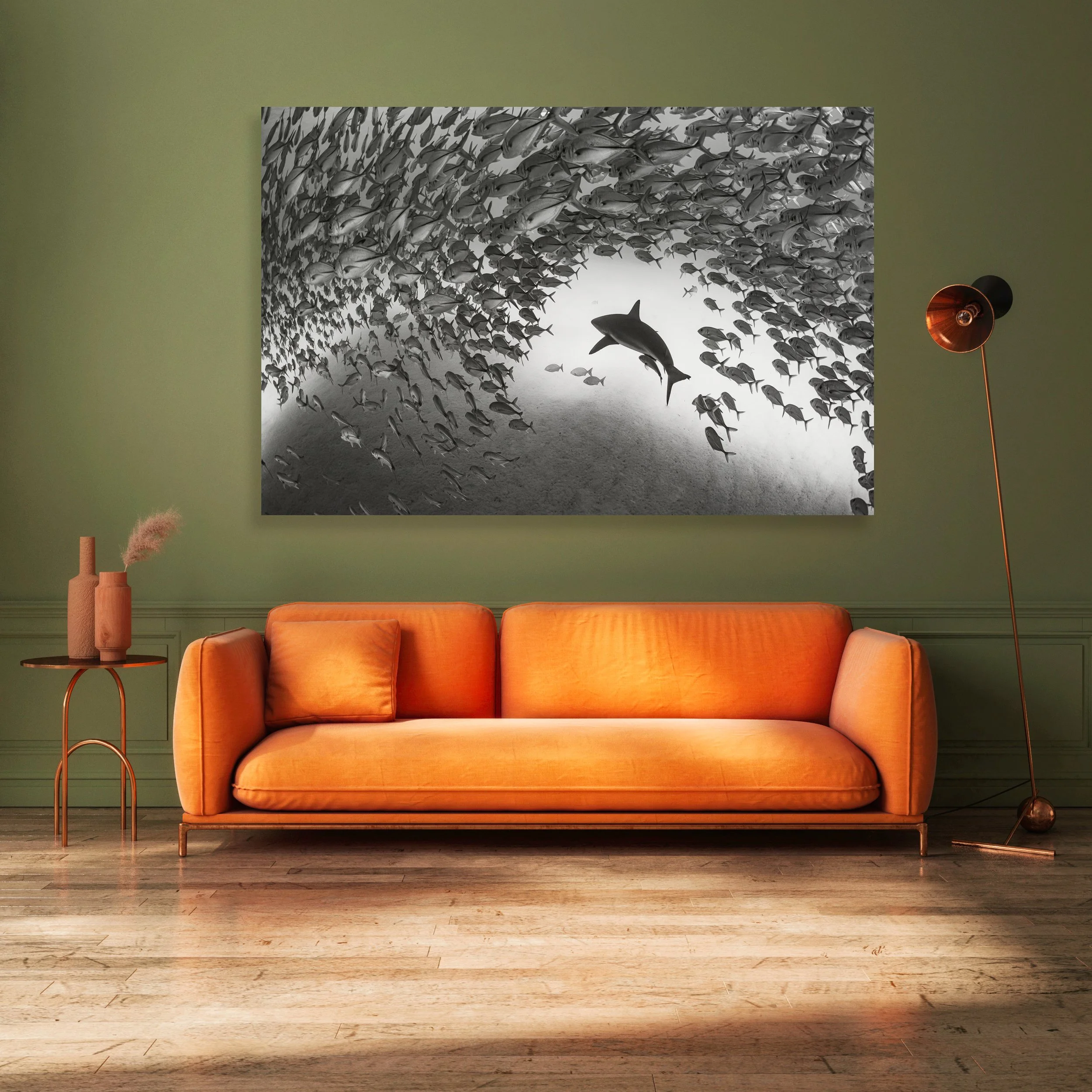 A black-and-white photograph of a school of fish forming a tunnel with a dolphin in the center, hanging on a green wall in a living room.