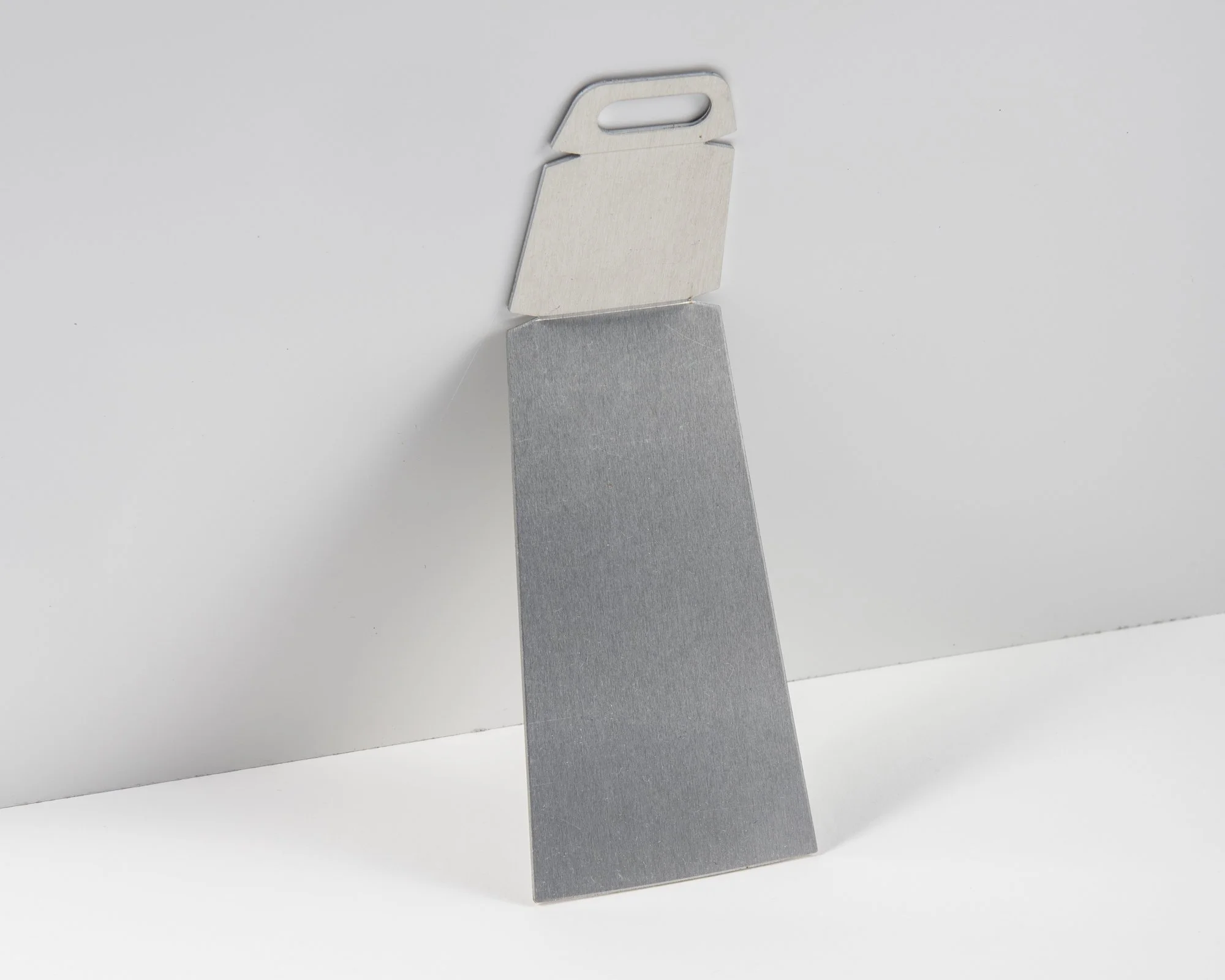 A razor blade with a silver metallic edge and a plastic handle, standing upright against a plain white background.