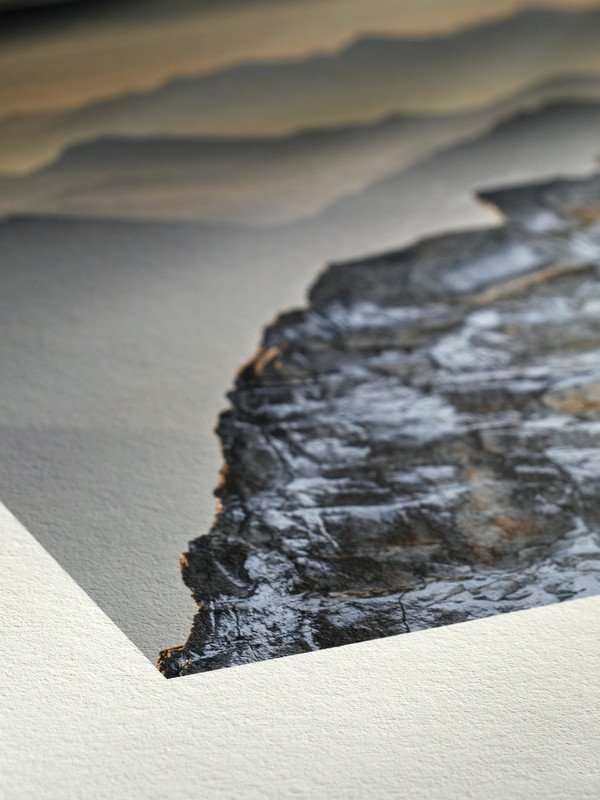Close-up of a printed photograph depicting layered rocks and sand patterns.
