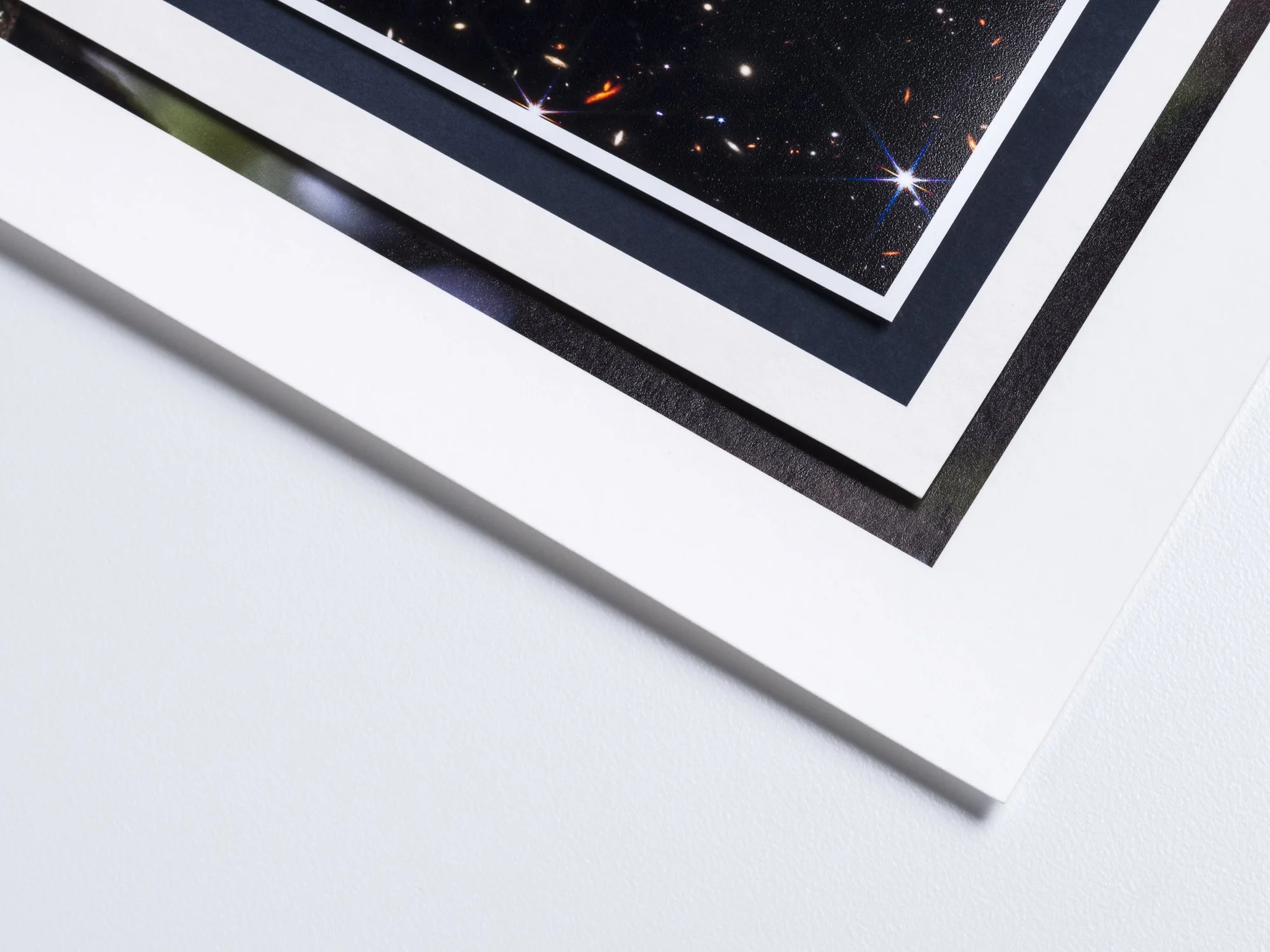 Close-up of four overlapping photographs, with the top one featuring a view of space with stars and nebulae.