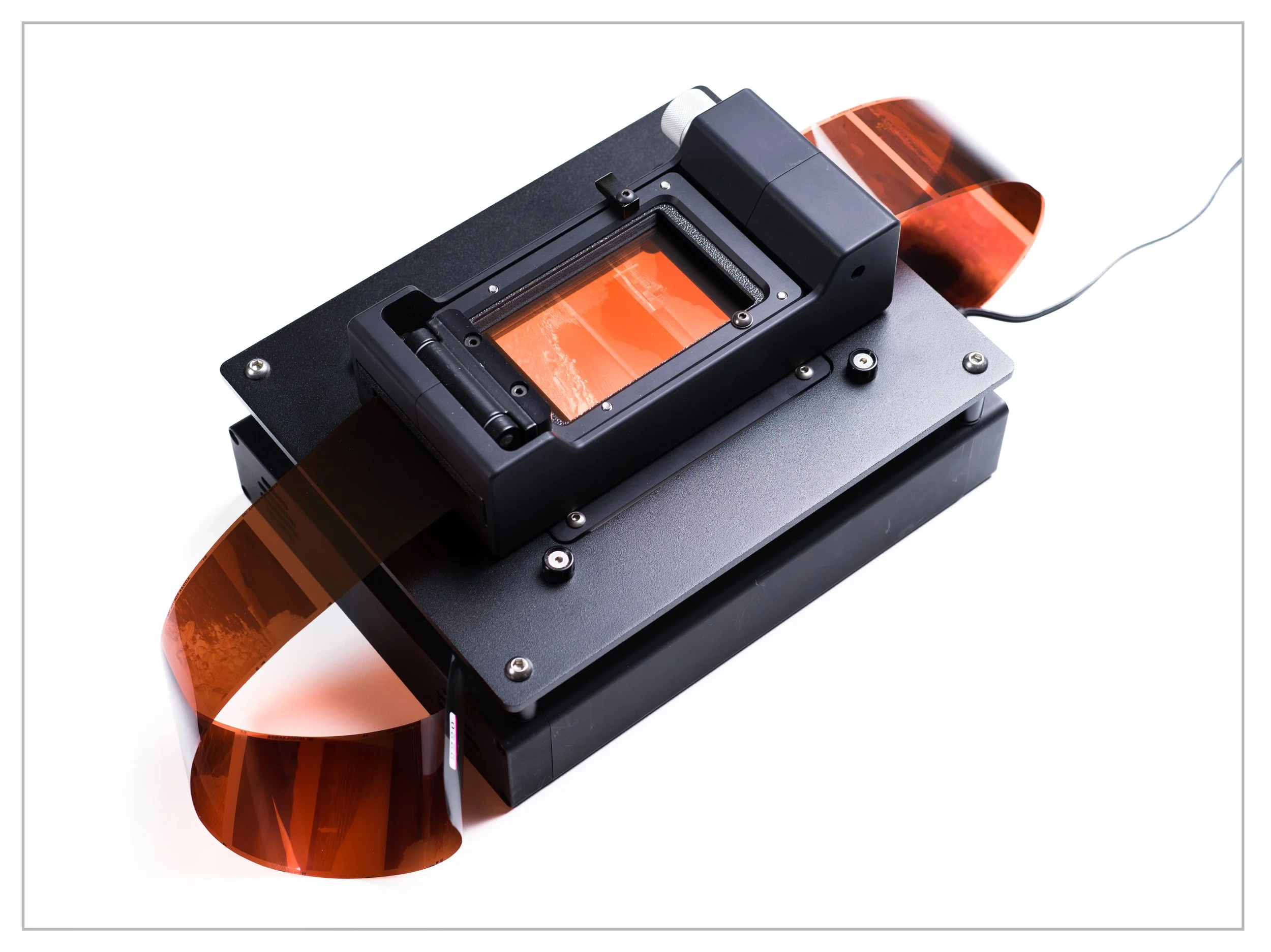 A device used for analyzing solar spectra, with a black rectangular body and orange-tinted glass or plastic components, connected to a power source.