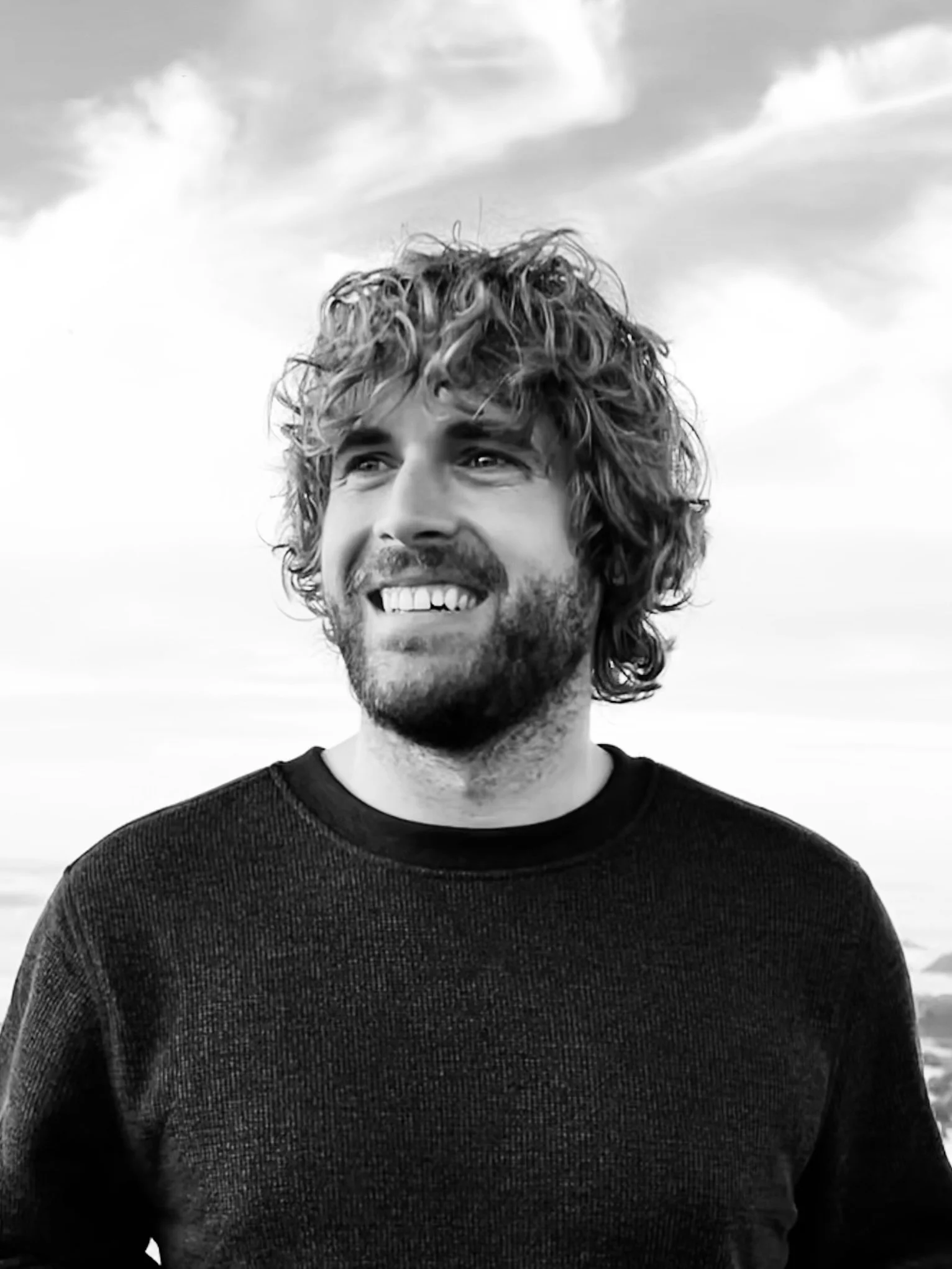 Portrait of Joe Platko, operations manager and photo instructor, smiling outdoors in a black and white photograph.