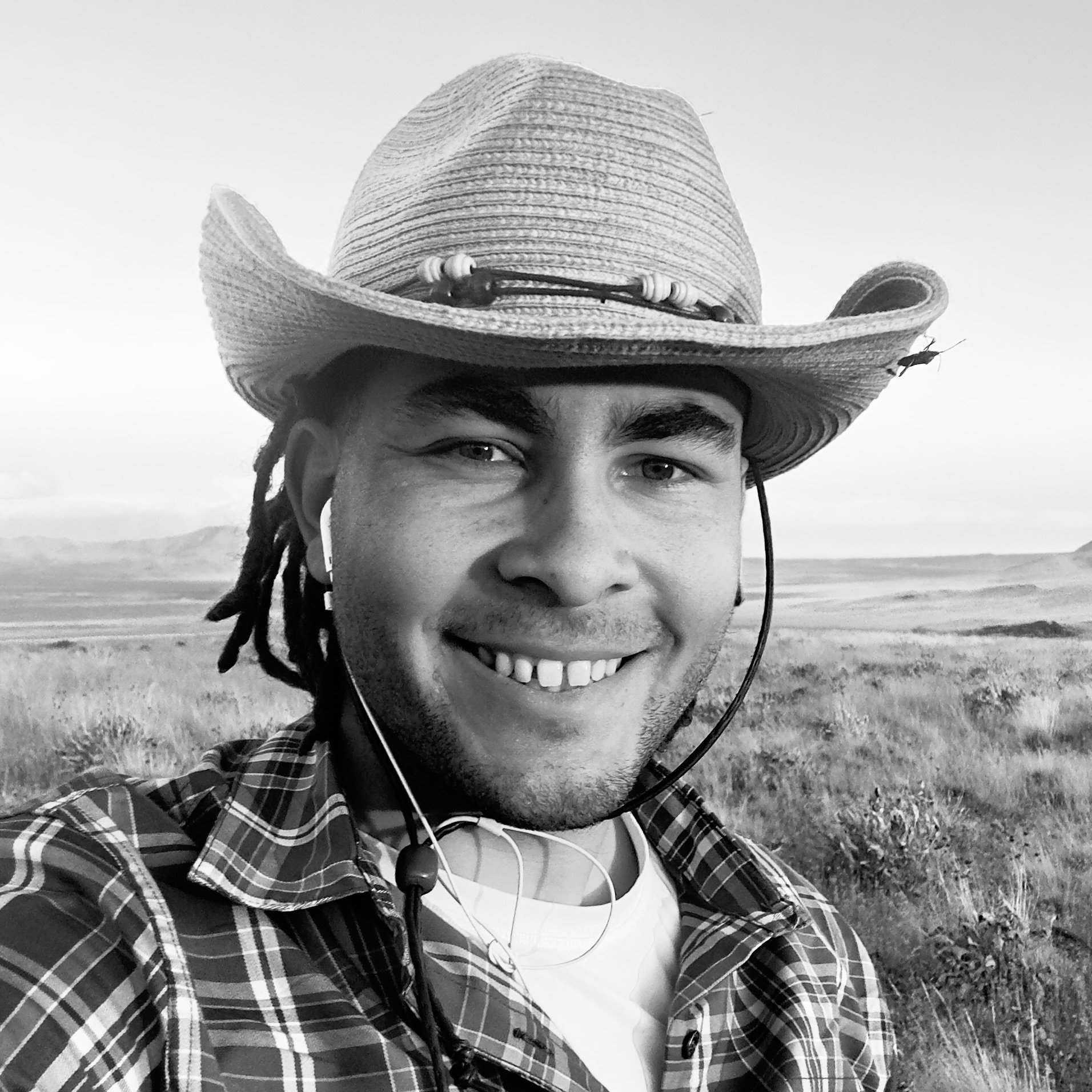 Black and white portrait of Michael Scholis, outreach and media strategist, wearing a hat and photographed outdoors.