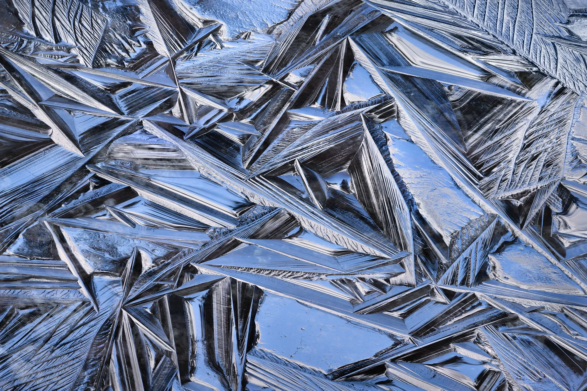 Abstract ice crystals forming sharp geometric patterns in cool blue tones.