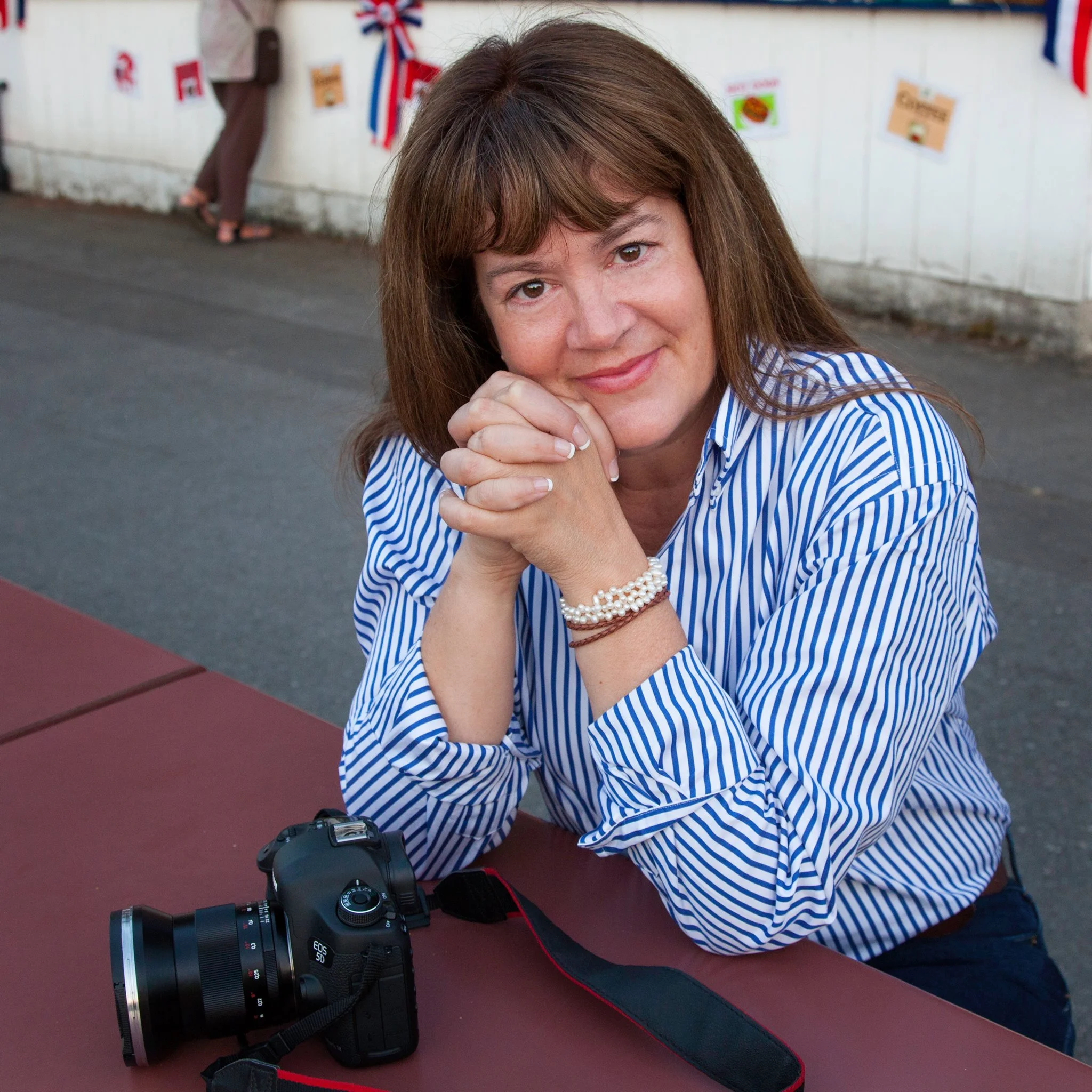 Portrait of photographer Keron Psillas seated outdoors with a camera resting on a table.
