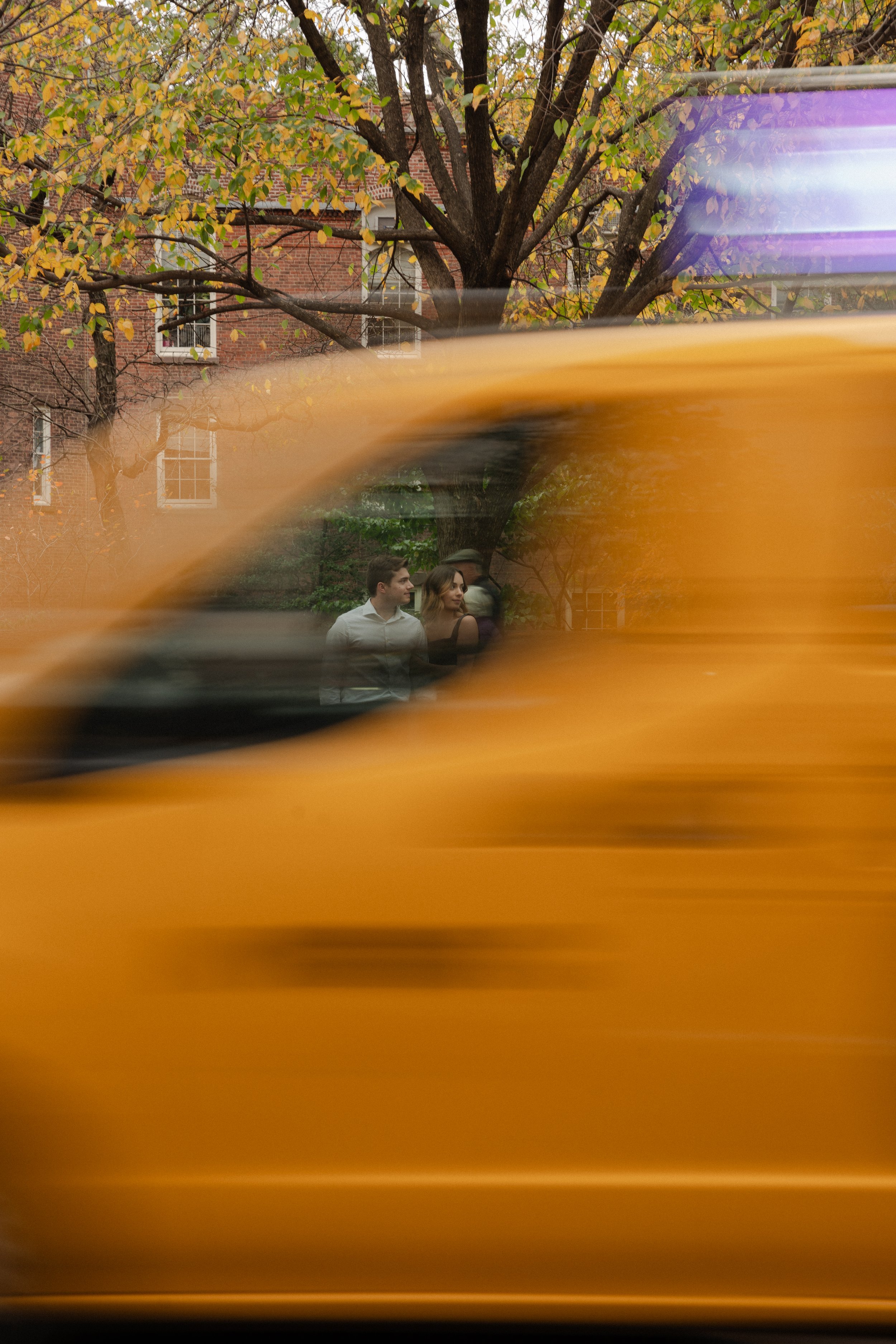 A blurred yellow vehicle in motion with a young couple for their engagement photos photographed by Dominique Paulette Photography