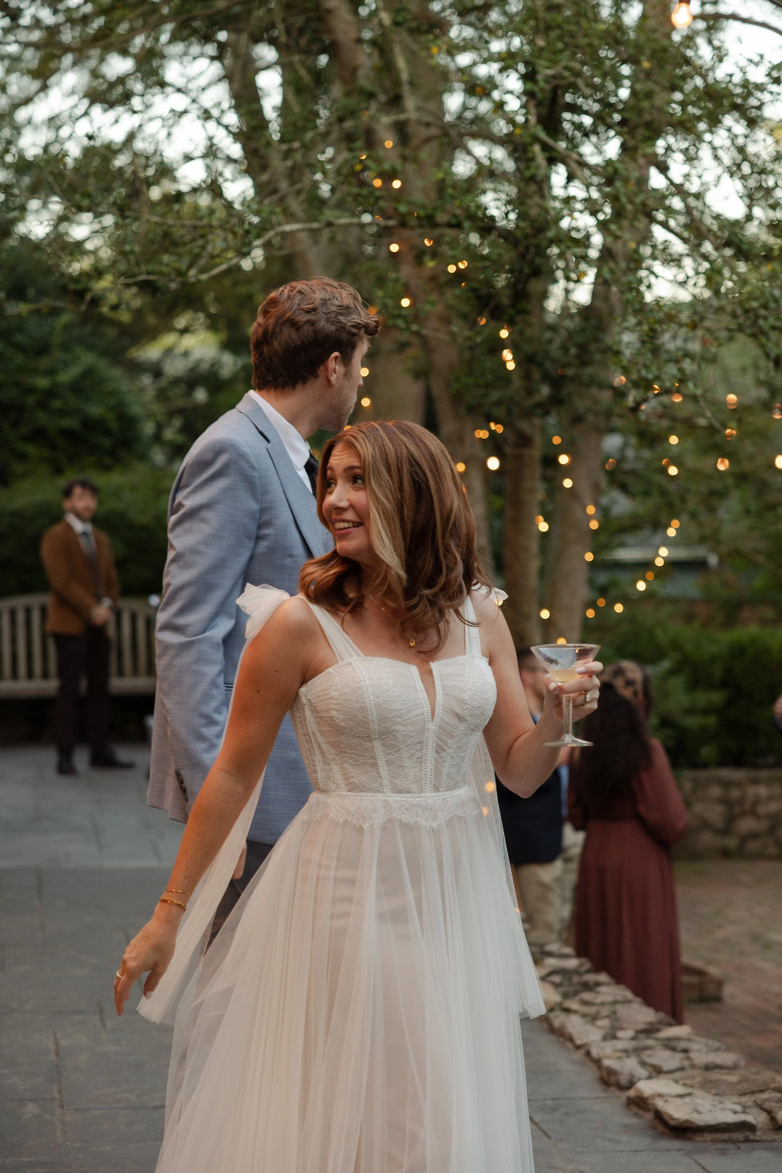 A woman in a wedding dress holding a drink and smiling with her husband at their wedding in Somerville, New Jersey photographed by Dominique Paulette Photography
