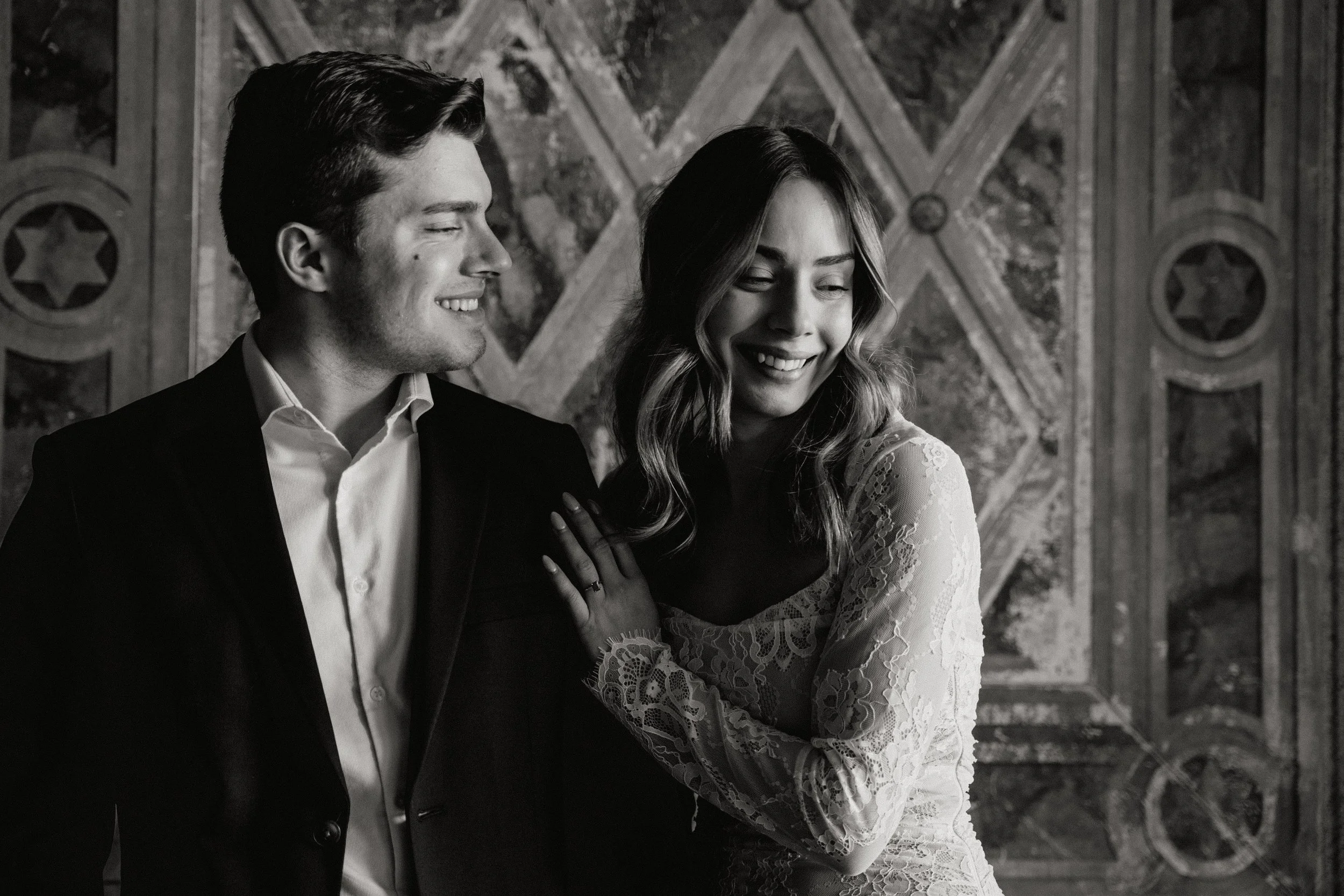 A black-and-white photo of a smiling couple standing close together for their engagement shoot in Somerville, New Jersey photographed by Dominique Paulette Photography