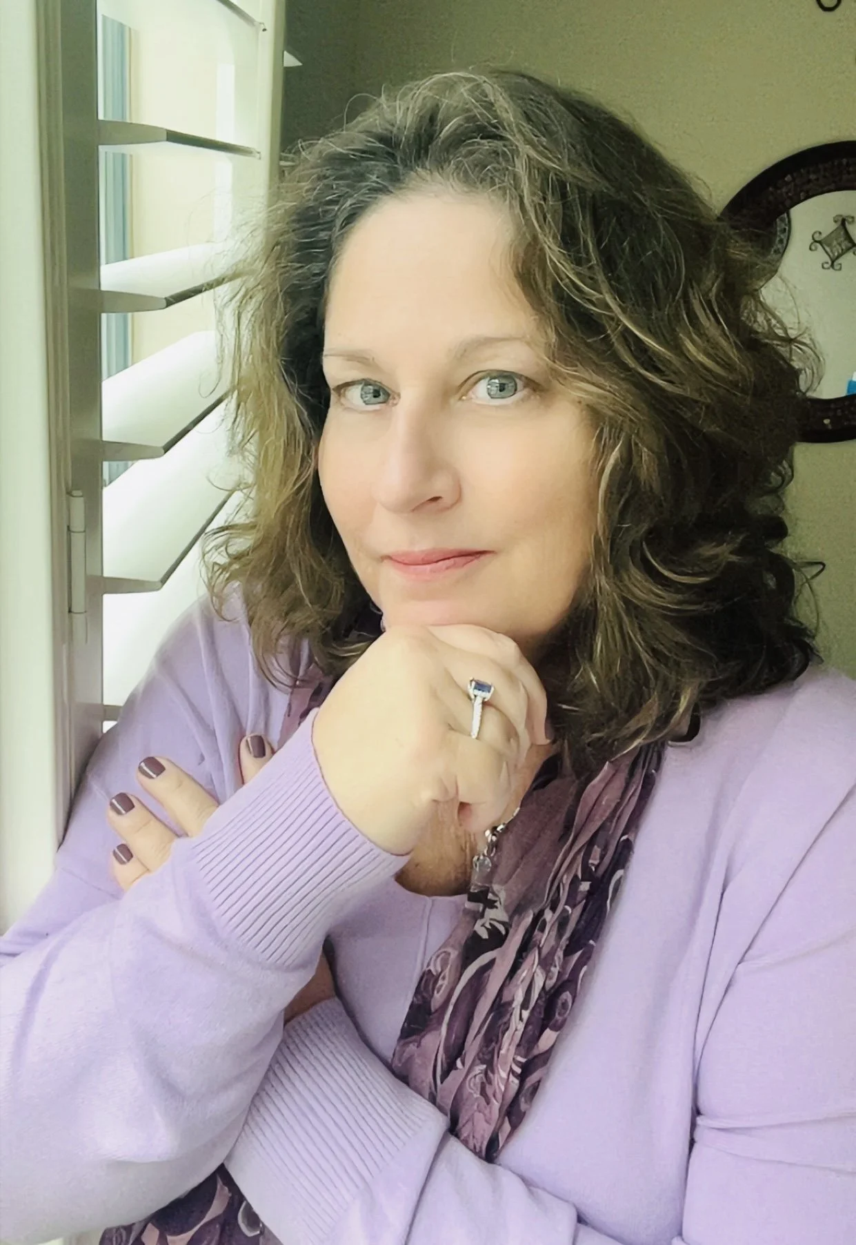 Middle aged woman wearing a purple sweater looking towards the camera.