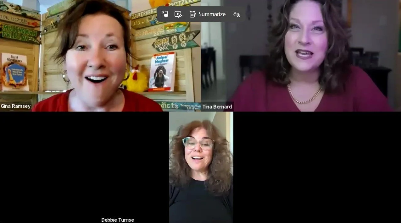 Three women participating in a video call. The woman on the left has short brown hair, earrings, and is wearing a red top. The woman on the right has shoulder-length curly hair, wearing a maroon top and a necklace. The woman at the bottom has curly hair, glasses, and is wearing a black top.