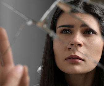 Close-up of a woman with long dark hair looking thoughtfully at a glass sculpture.