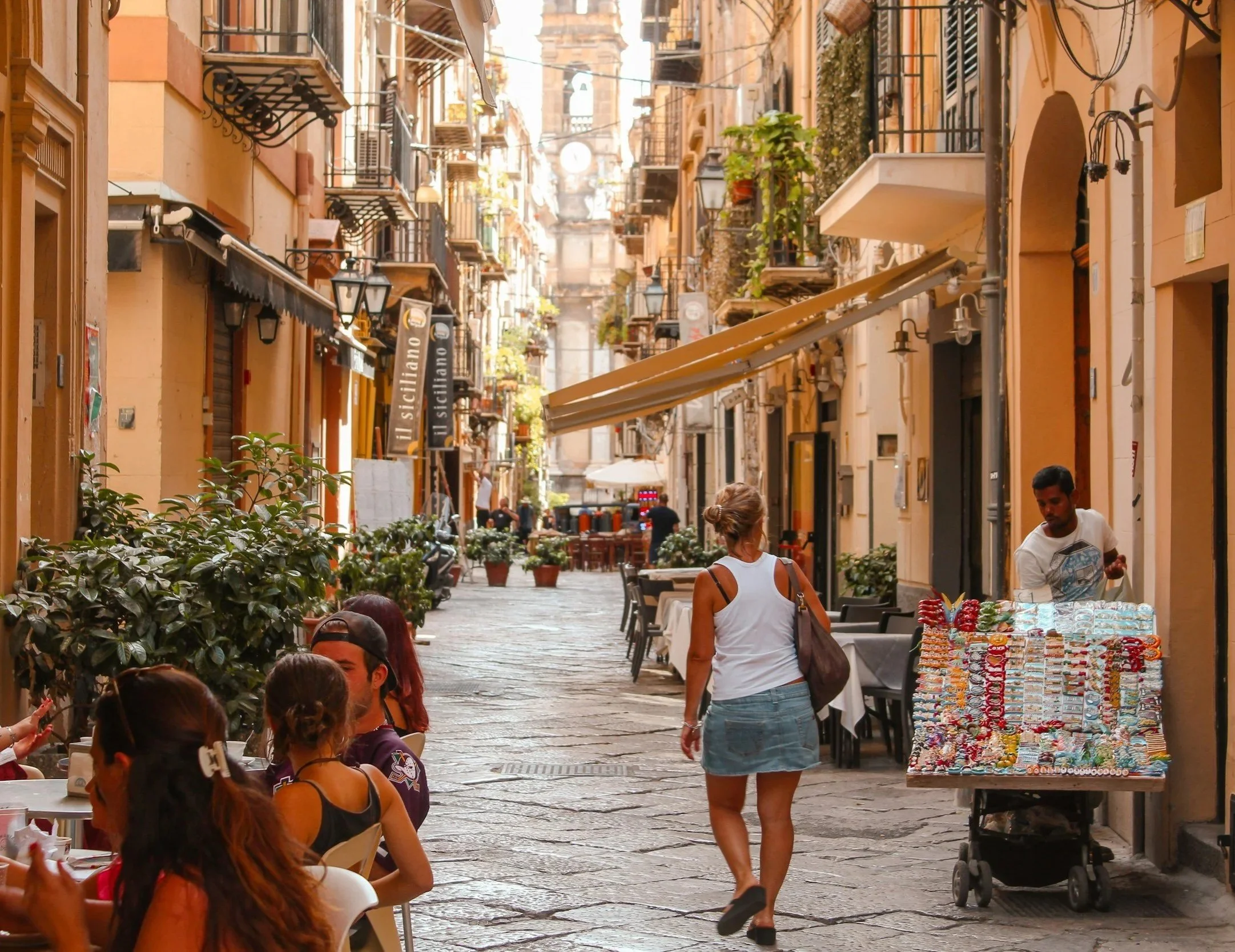 Atmospheric Italian street with outdoor cafés, traditional buildings and local shops, capturing the charm of a shore excursion from a yacht charter in the Aeolian Islands