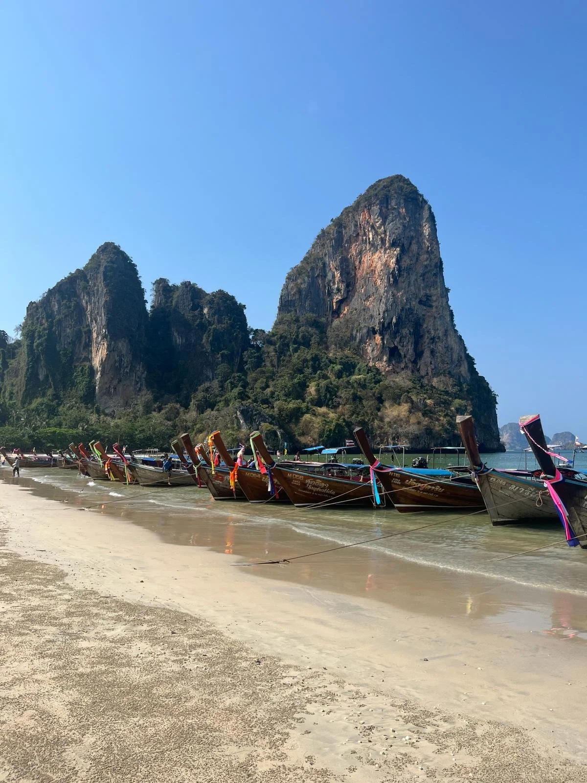 Longtail boats on Railay Beach, Thailand, beneath dramatic limestone cliffs