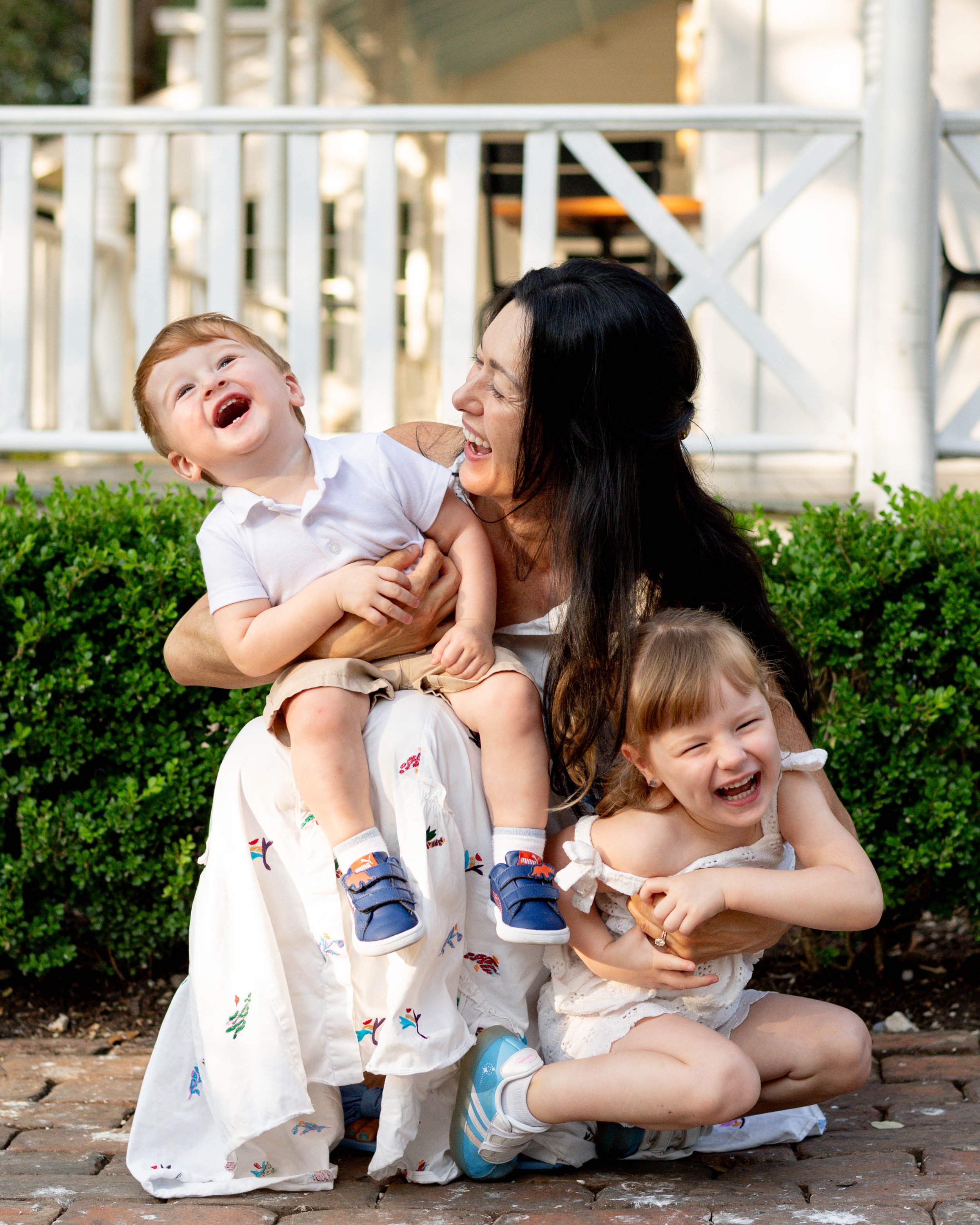Laughing mother holding two young children during an outdoor family photography session by Austin, Texas photographer Lani Tons