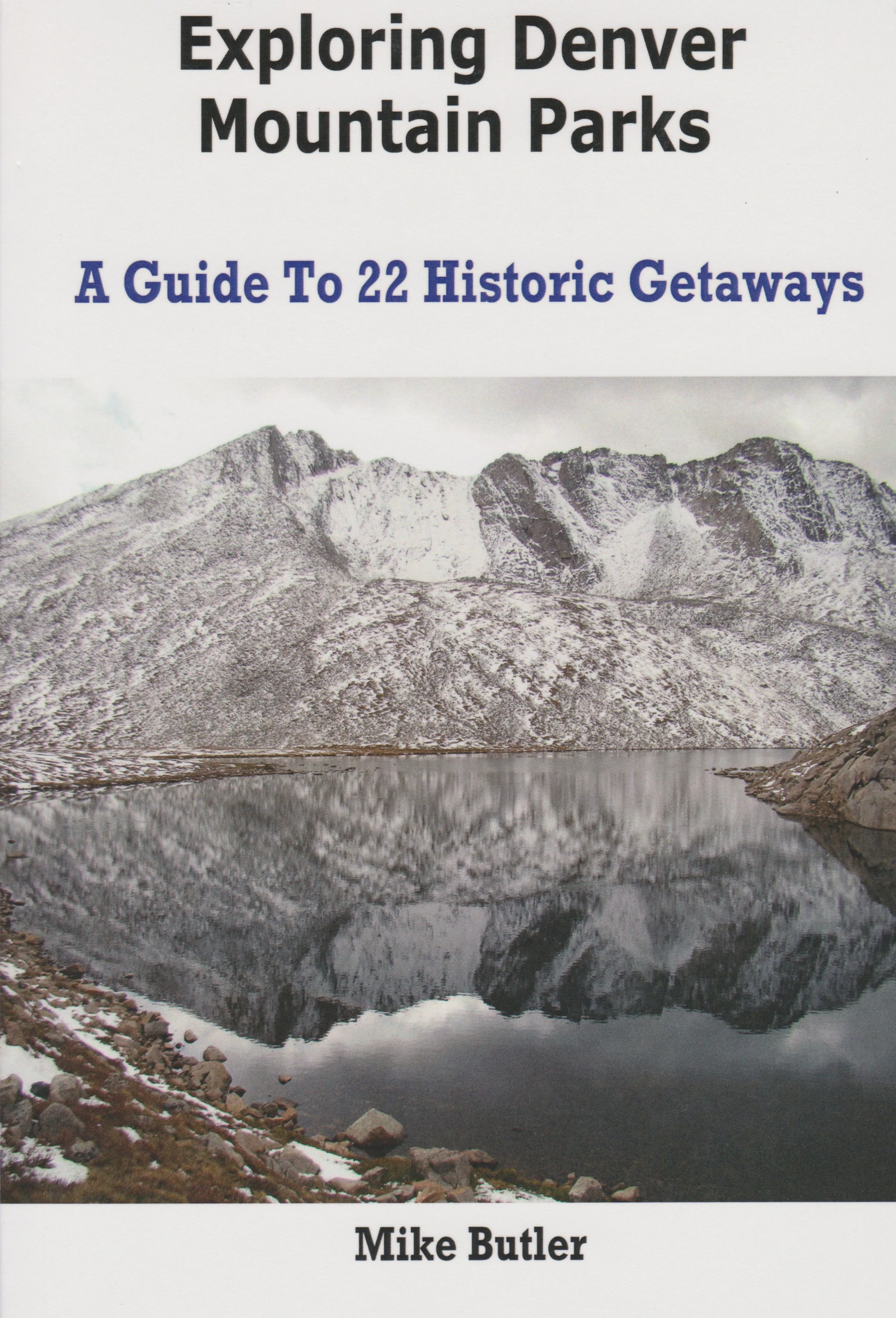 Book cover titled "Exploring Denver Mountain Parks: A Guide to 22 Historic Getaways" by Mike Butler, featuring a black-and-white photograph of a mountain range reflected in a lake.