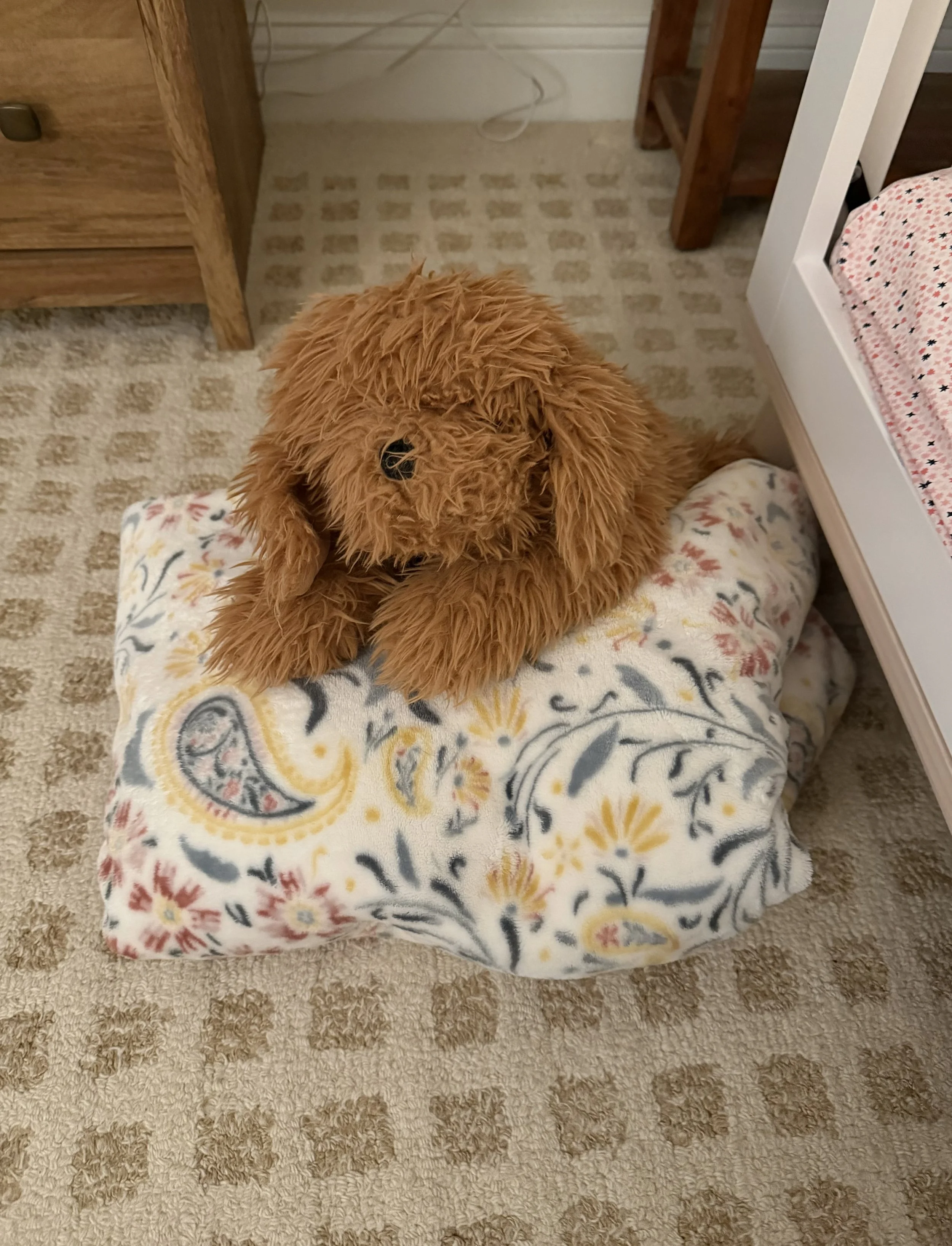 Stuffed puppy on top of a folded blanket on the floor