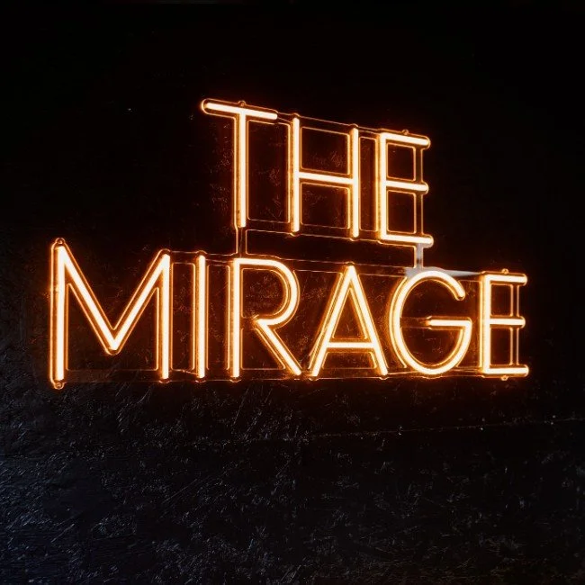 Neon sign reading 'THE MIRAGE' in bright orange against a dark background.