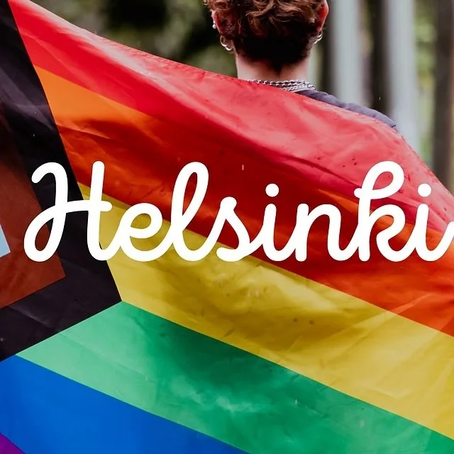 Person holding a rainbow pride flag with the word 'Helsinki' written across it
