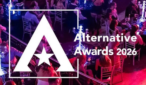 Crowd attending an awards ceremony sitting at tables with wine glasses, with a large logo and the text 'Alternative Awards 2026' overlayed.