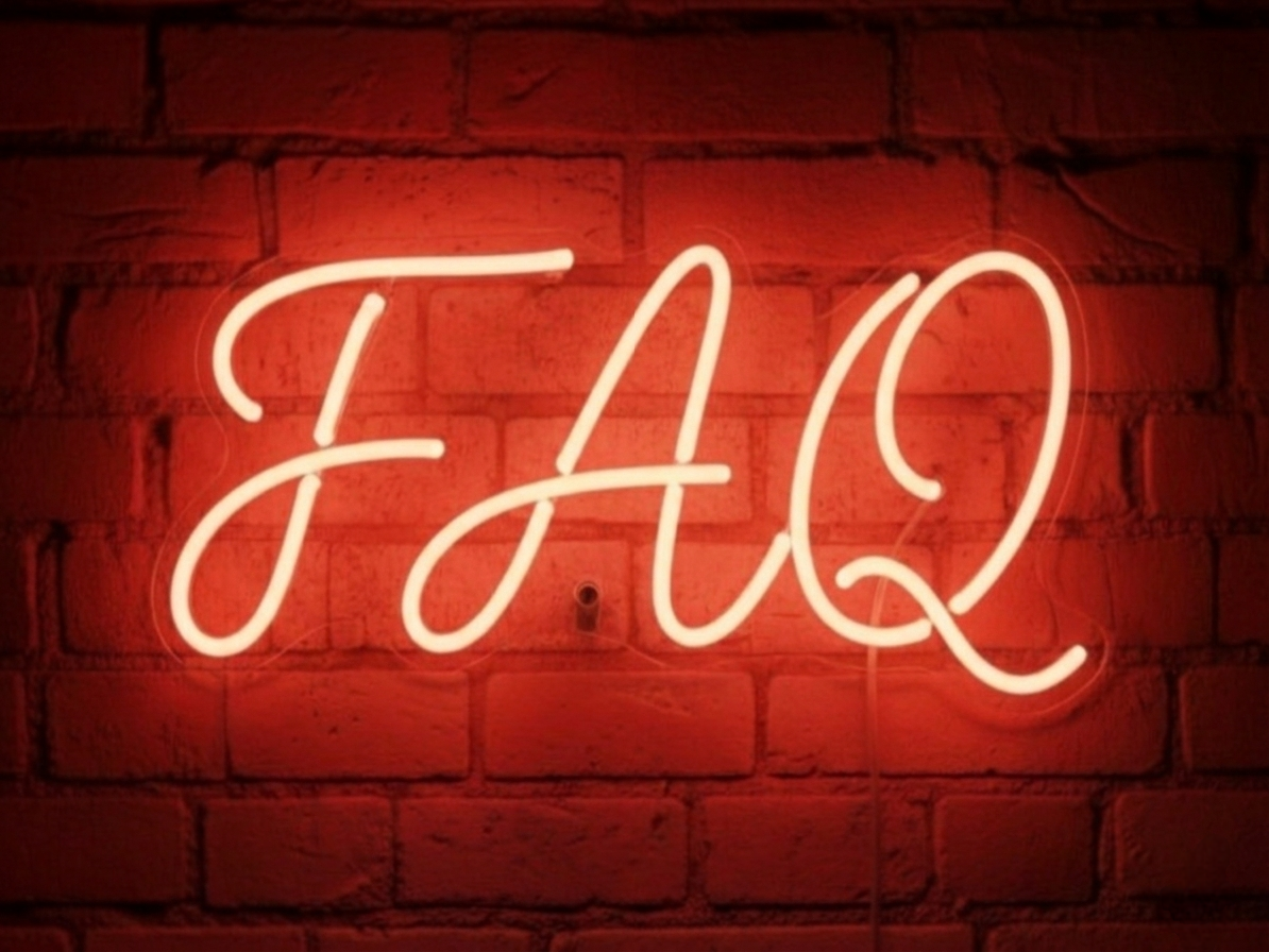 Neon sign on brick wall that reads 'EAT' in cursive white script.