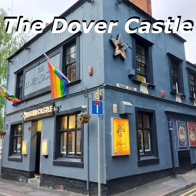The Dover Castle, a pub with blue exterior walls, decorated with rainbow flags and a star-shaped light on the corner, street signs, and posters on the windows.