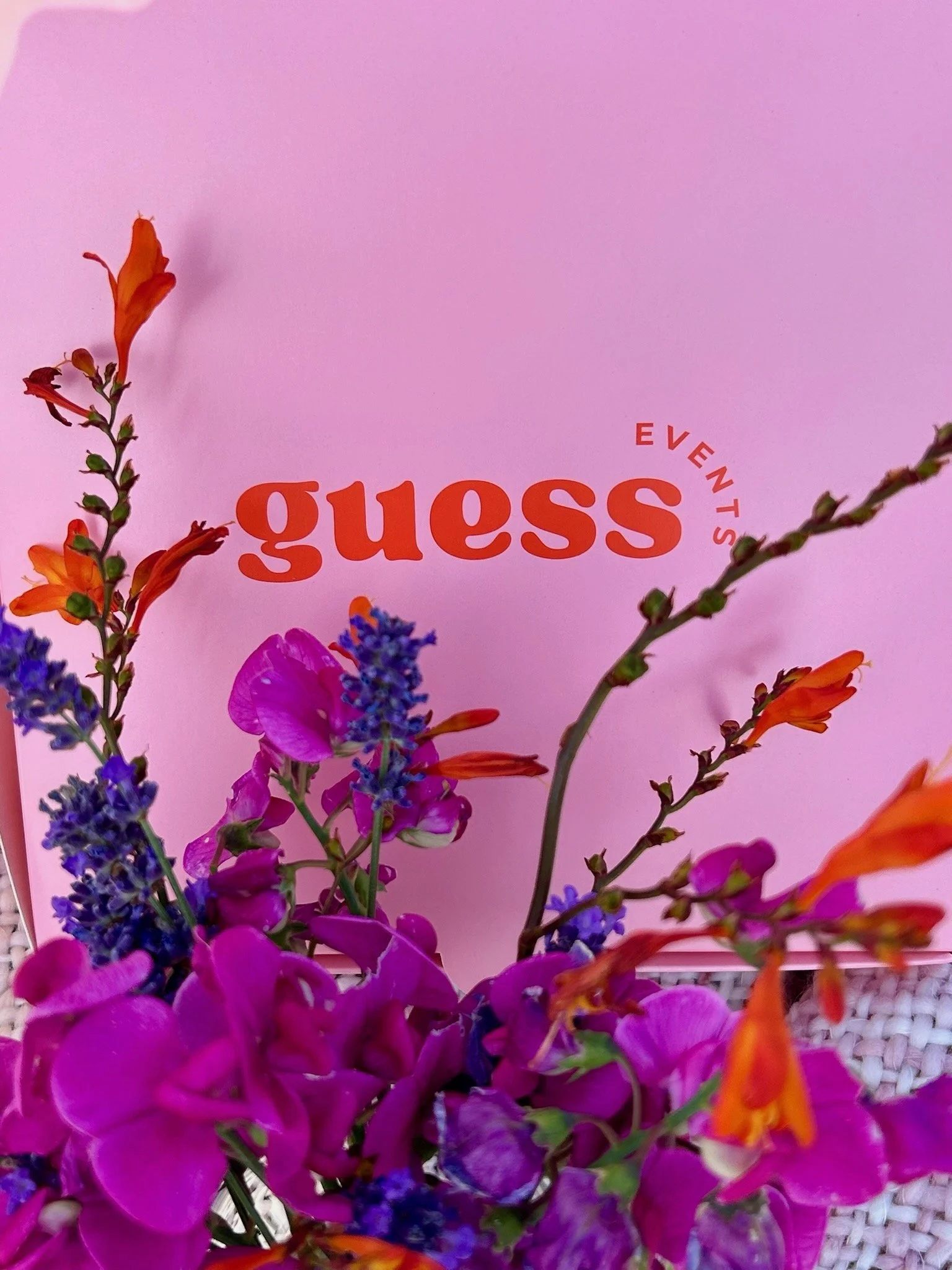 Pink Guess Events box with colorful flowers. get in touch to book our mobile food bars, charcuterie bars, dessert bars, picnic hampers and event catering across Devon, Cornwall and the South West.