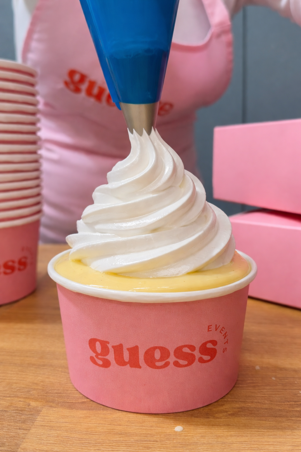 A Guess Events branded cup filled with warm apple crumble and custard topped with Italian meringue, served live at the Guess Events dessert bar across Devon, Cornwall and the South West.