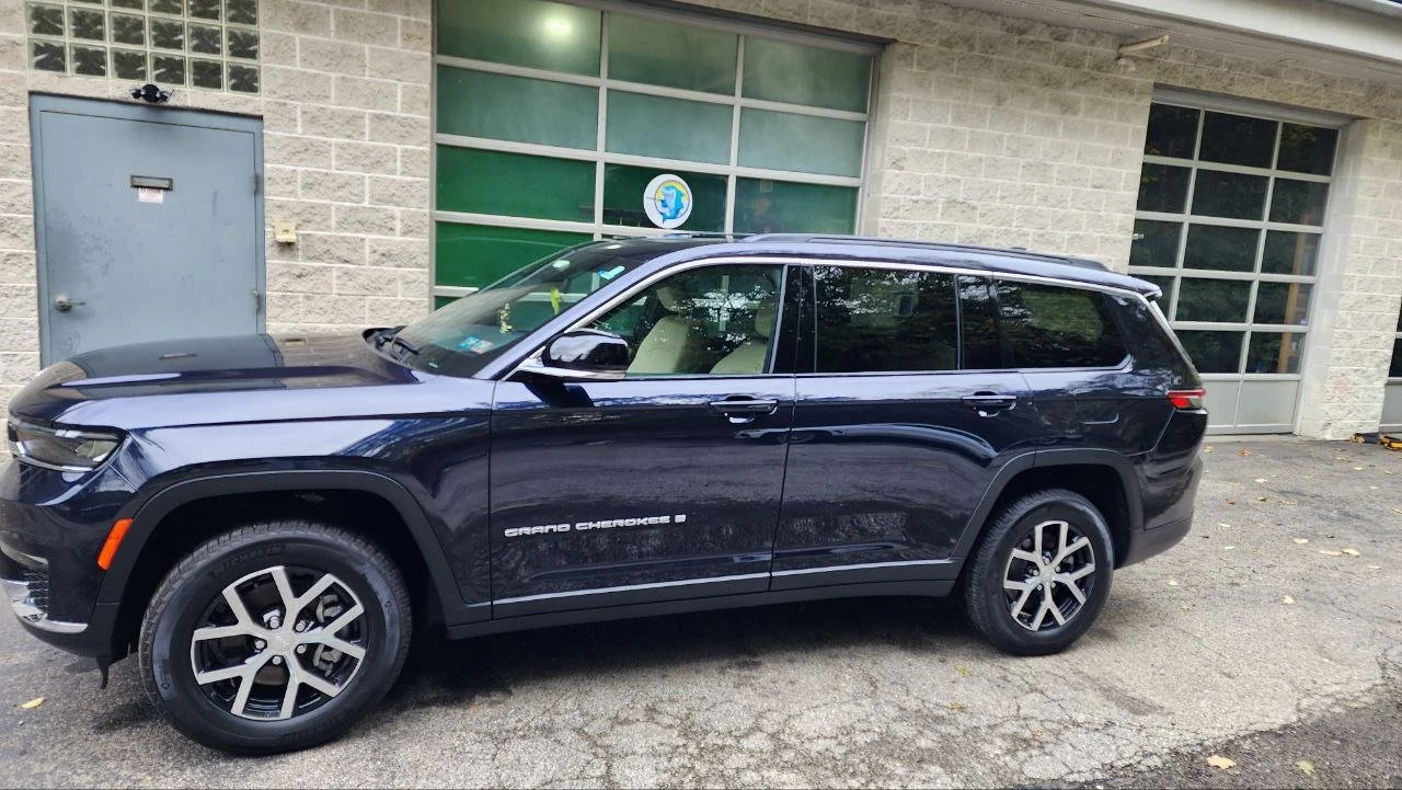 A black Jeep Grand Cherokee parked outside a building with large windows and a gray door.