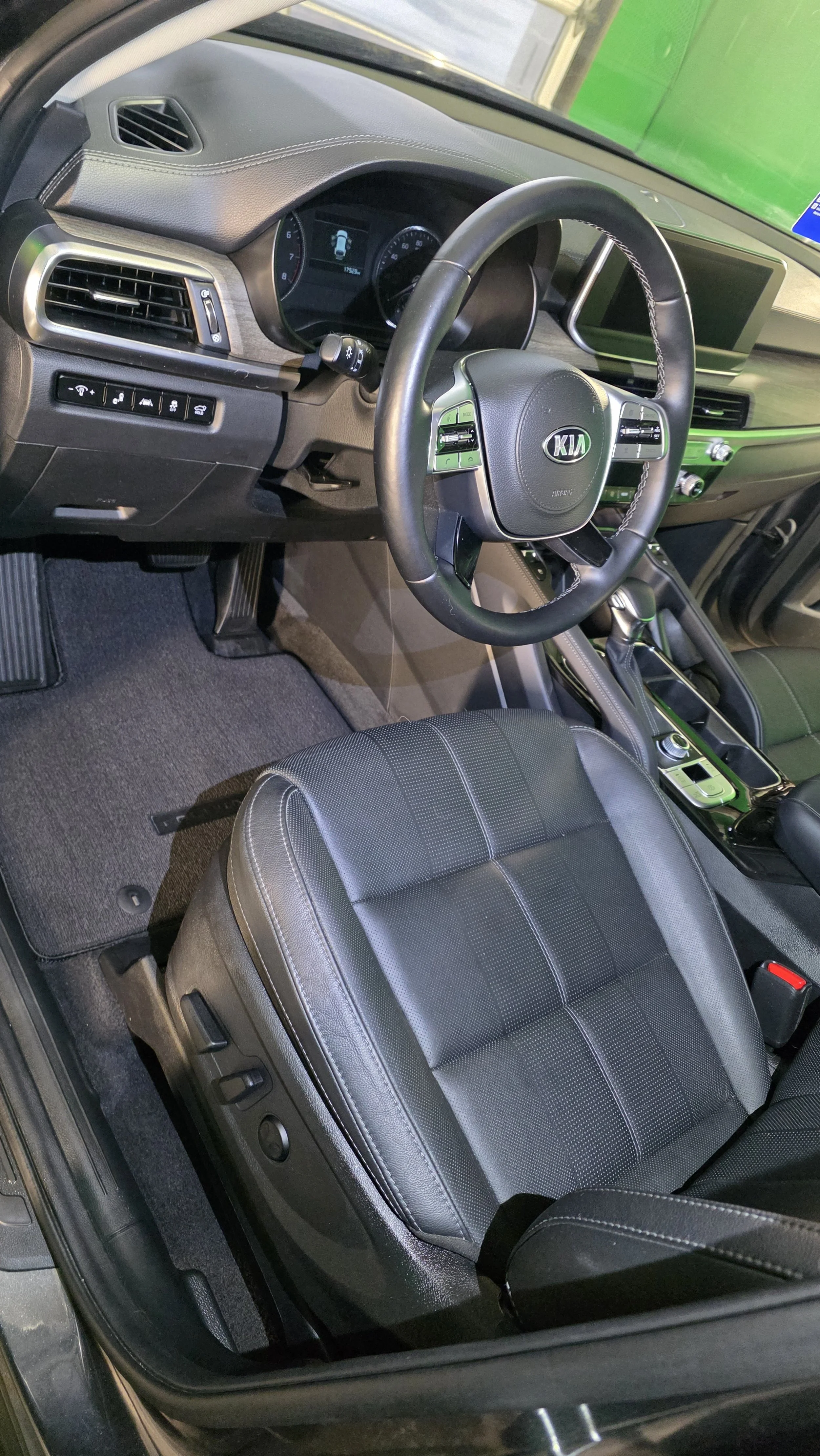 Interior of a Kia vehicle, showing the dashboard, steering wheel, center console, and front seat.