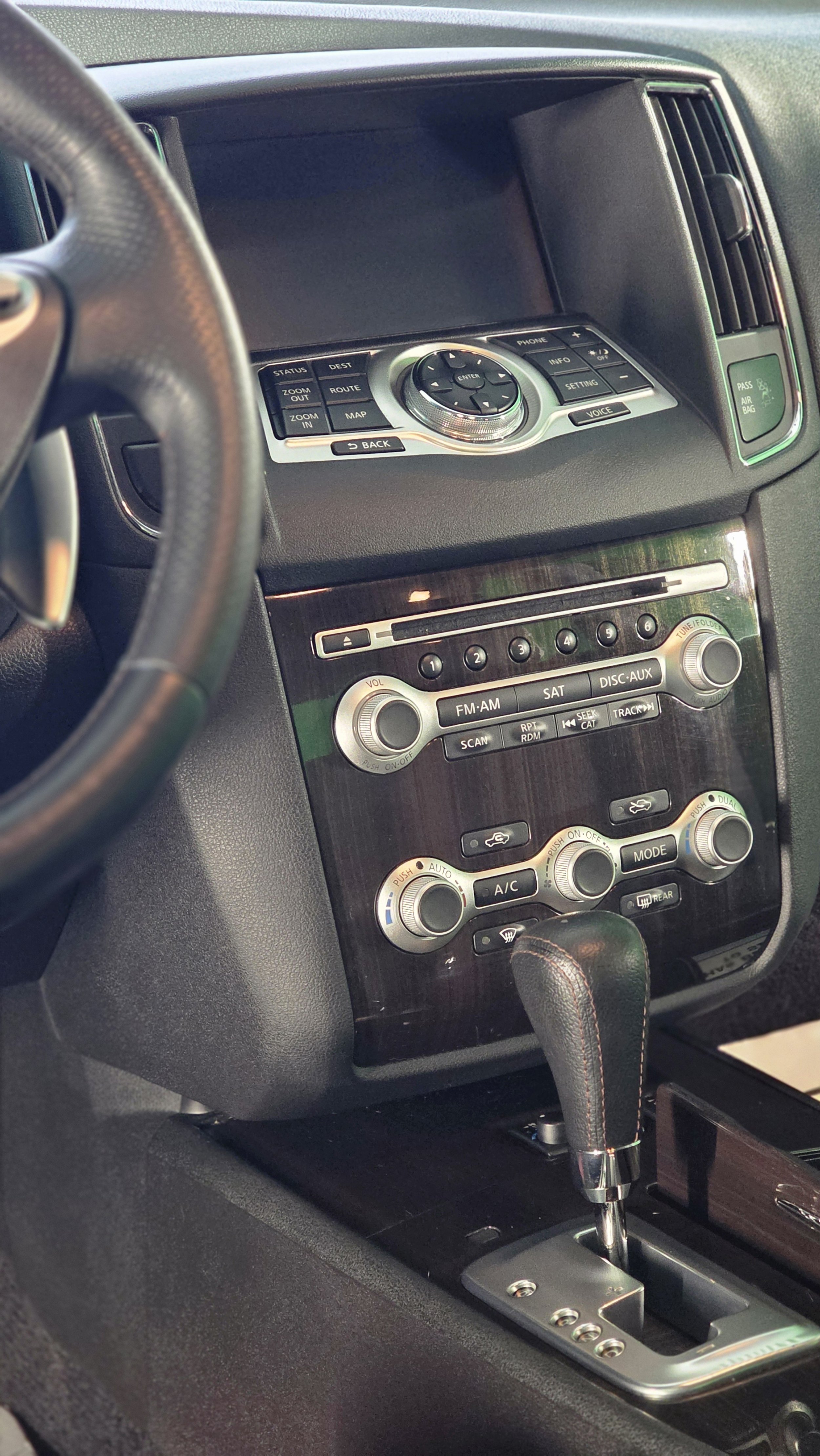 The interior of a car dashboard showing an entertainment system with radio controls, climate controls, and a gear shifter.