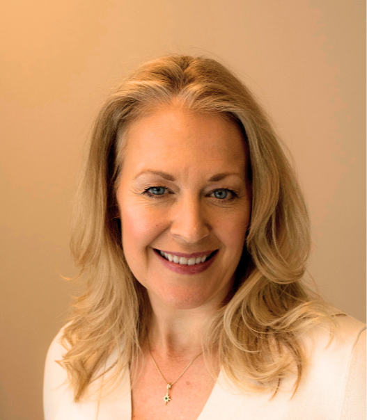 A smiling woman with blonde hair in a white top against a neutral background.