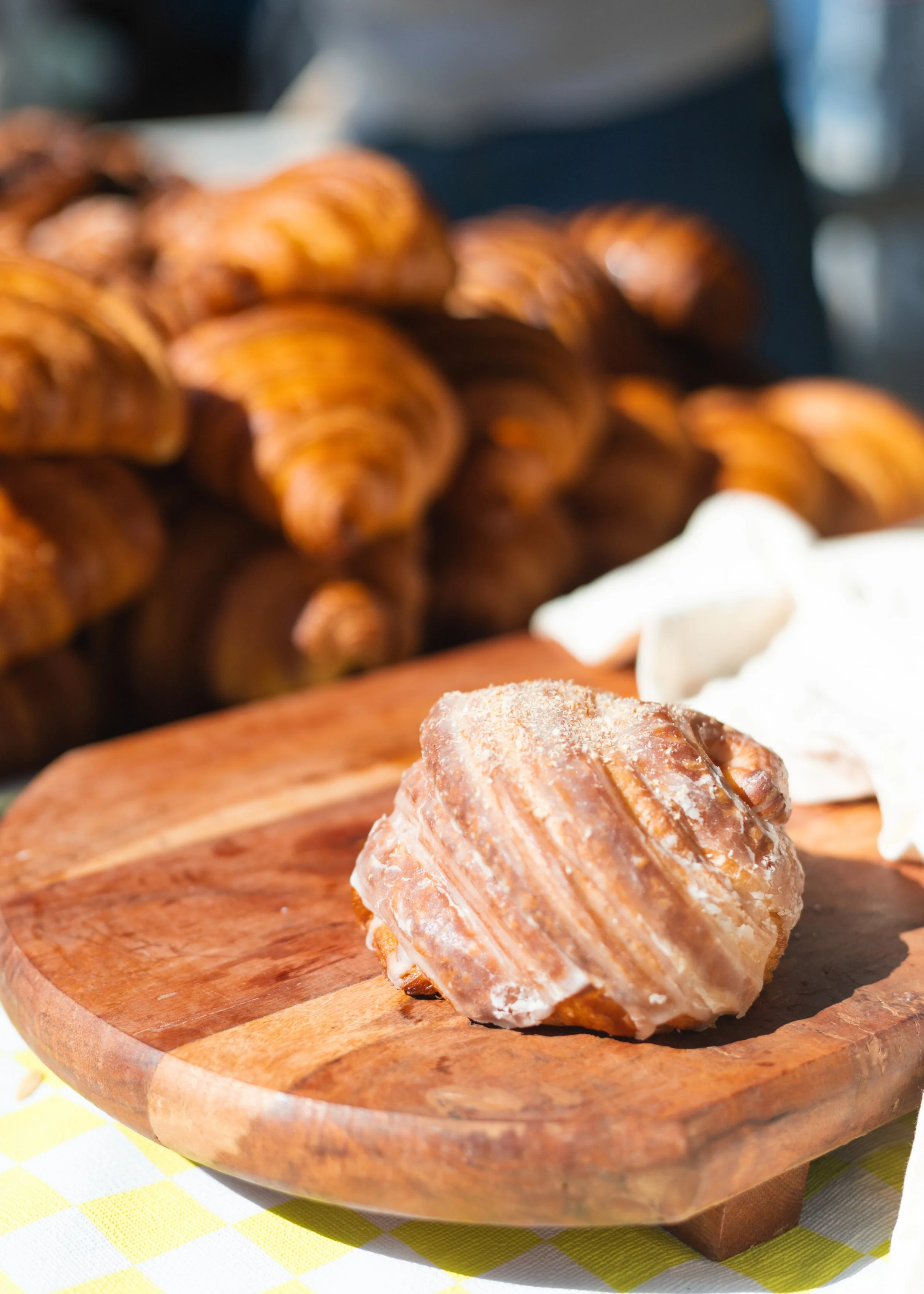 A close-up of a lime croissant on a wooden plate with more croissants in the background.