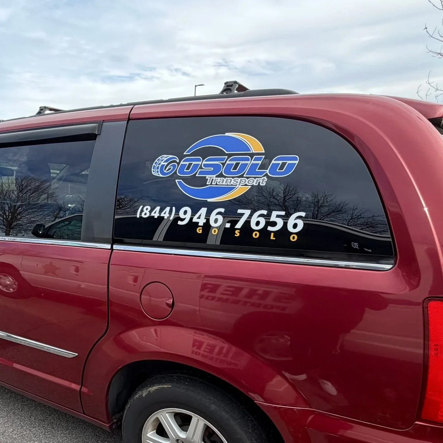 Red van with a logo and phone number for GoSolo Transport on the window.