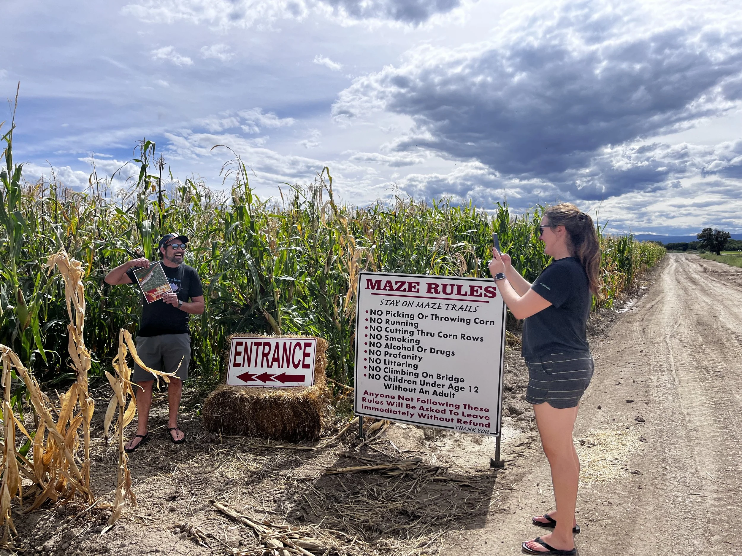 Josh and Kelsey beside the entrance and rules sign at the corn maze in Olathe, Colorado.