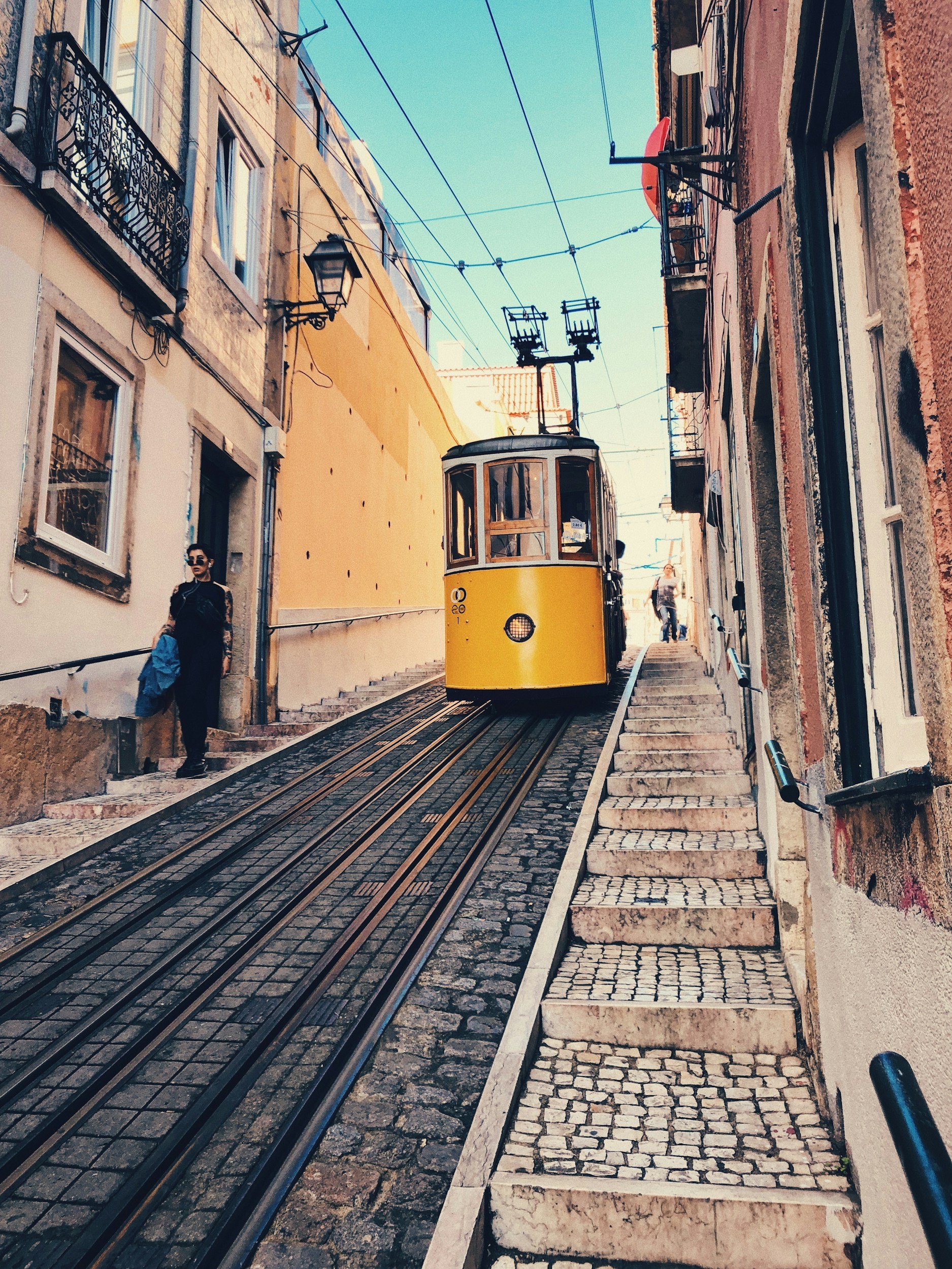Yellow funicular traveling up a steep street in Lisbon, Portugal