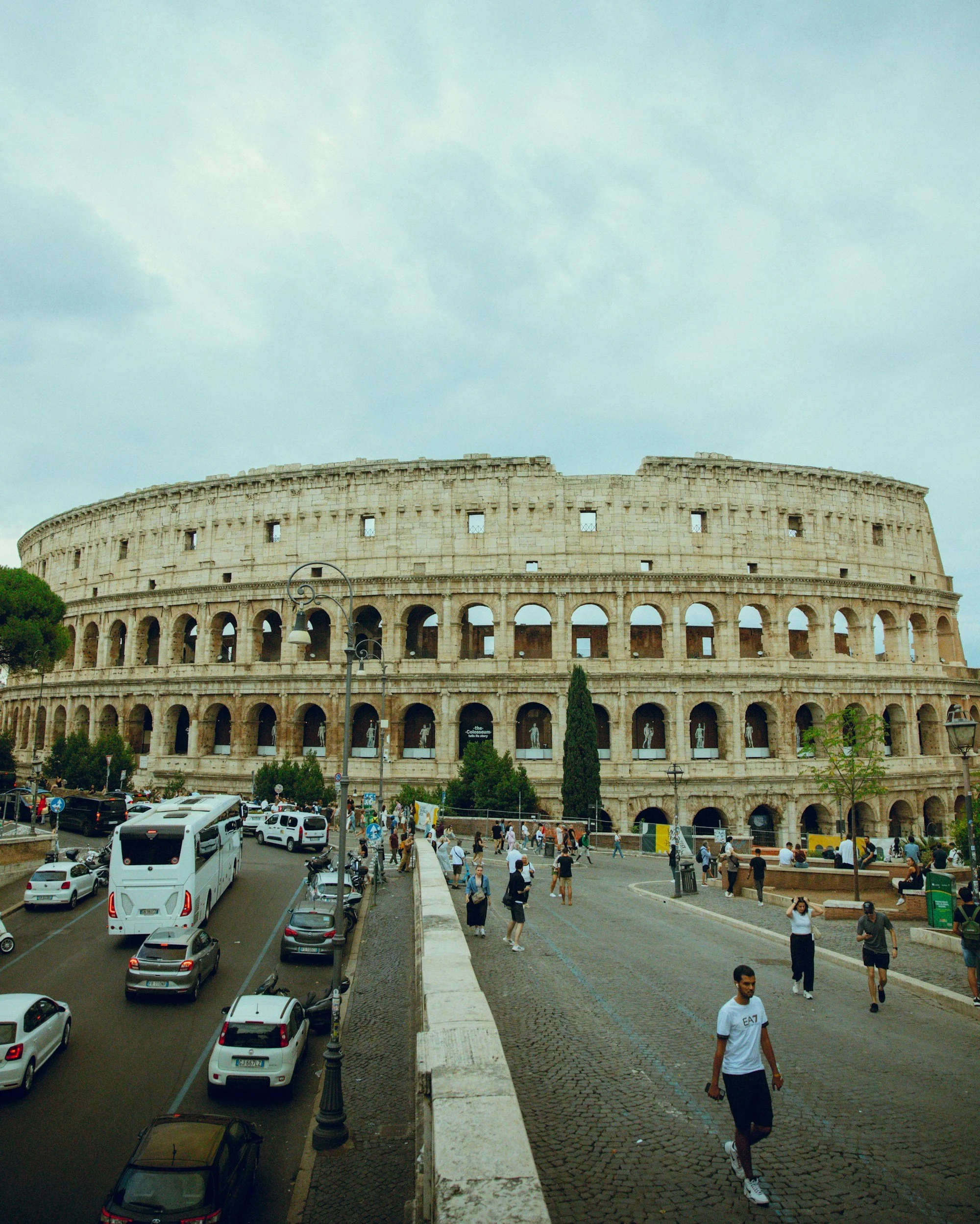 The Colosseum in Rome with buses, cars, and pedestrians traveling nearby