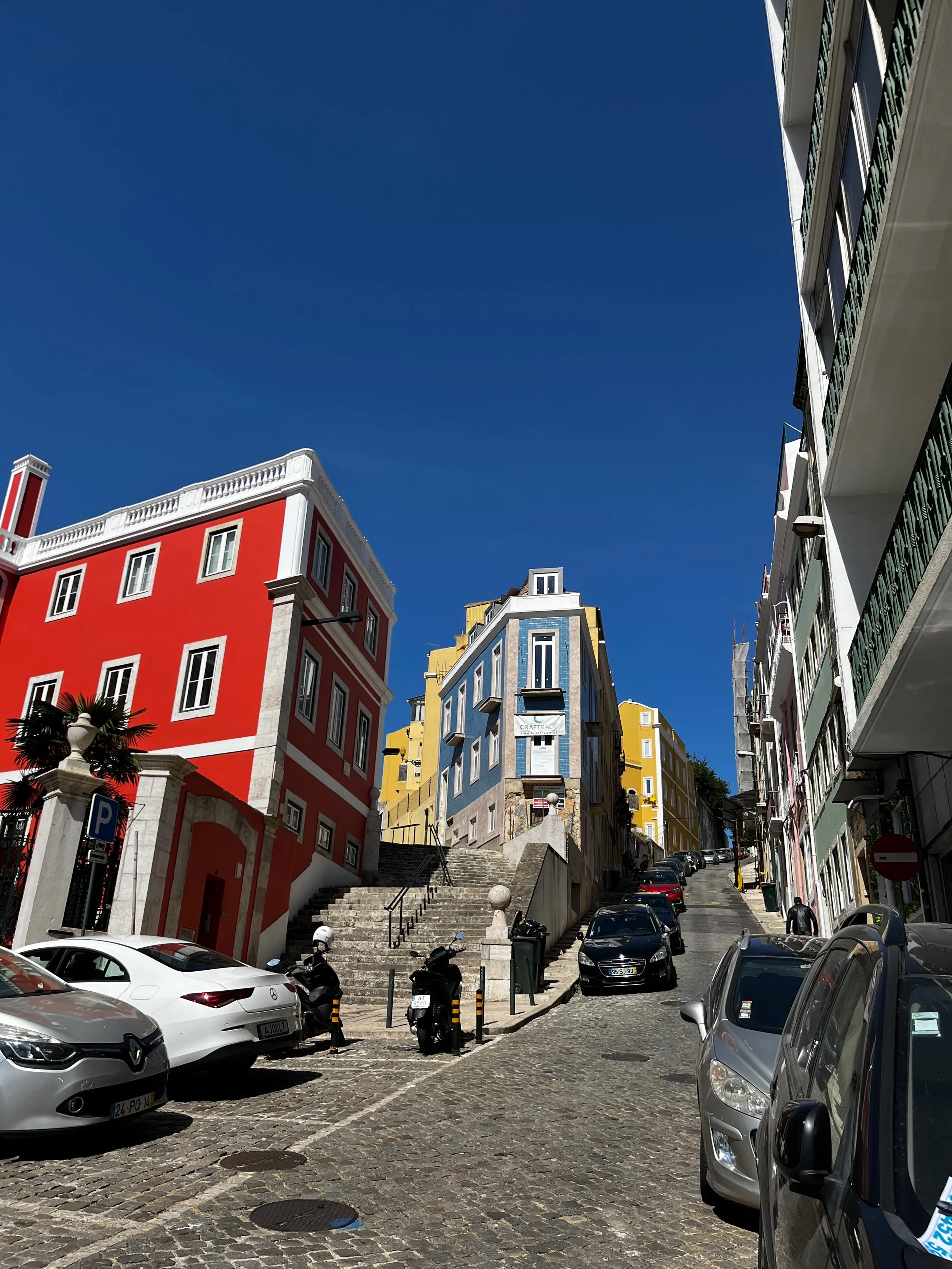 Colorful buildings and steep cobblestone streets while walking through Alcântara in Lisbon, Portugal.