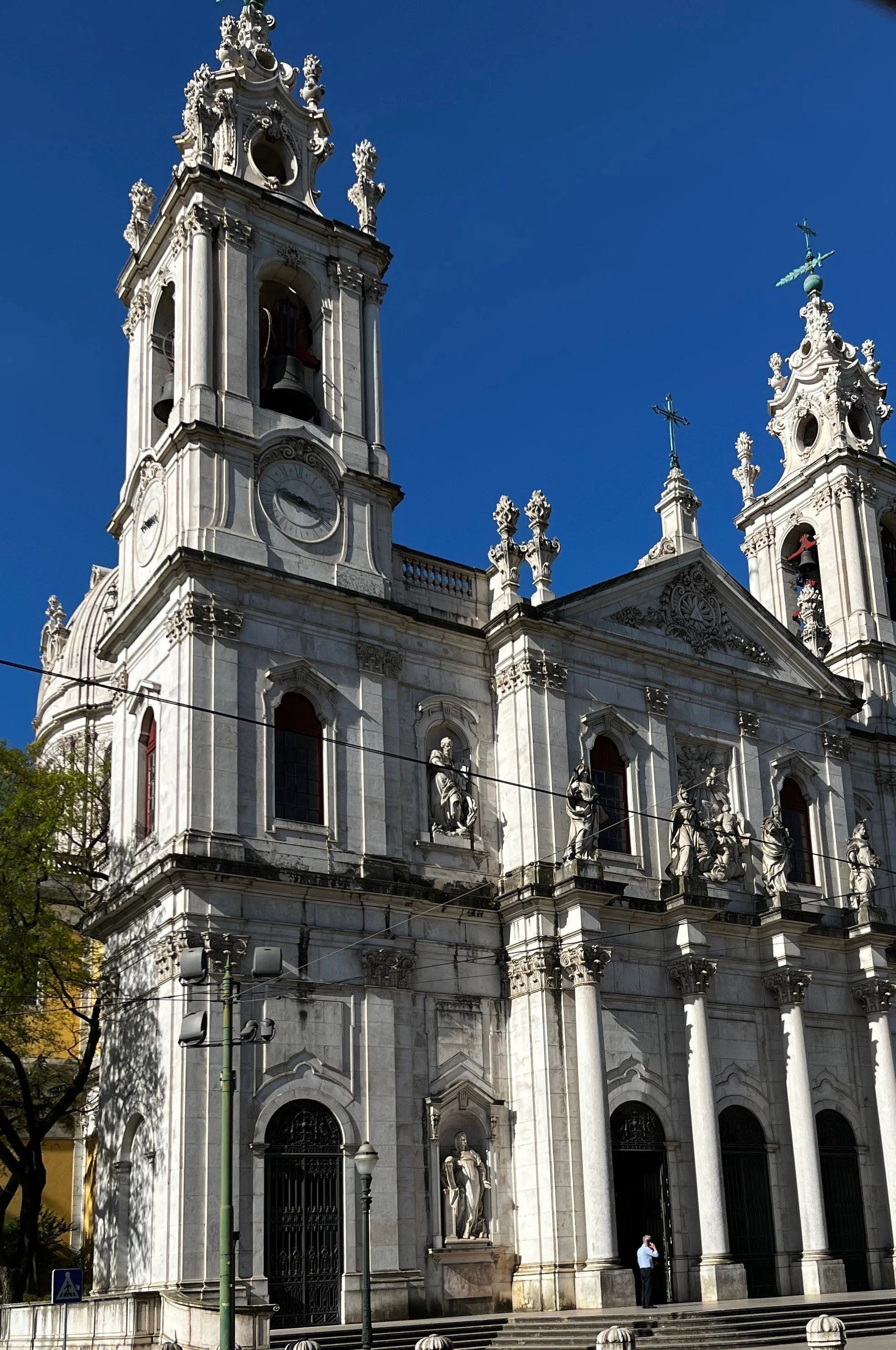 Ornate white stone façade of the Basílica da Estrela in Lisbon, Portugal, with columns, statues and bell towers.