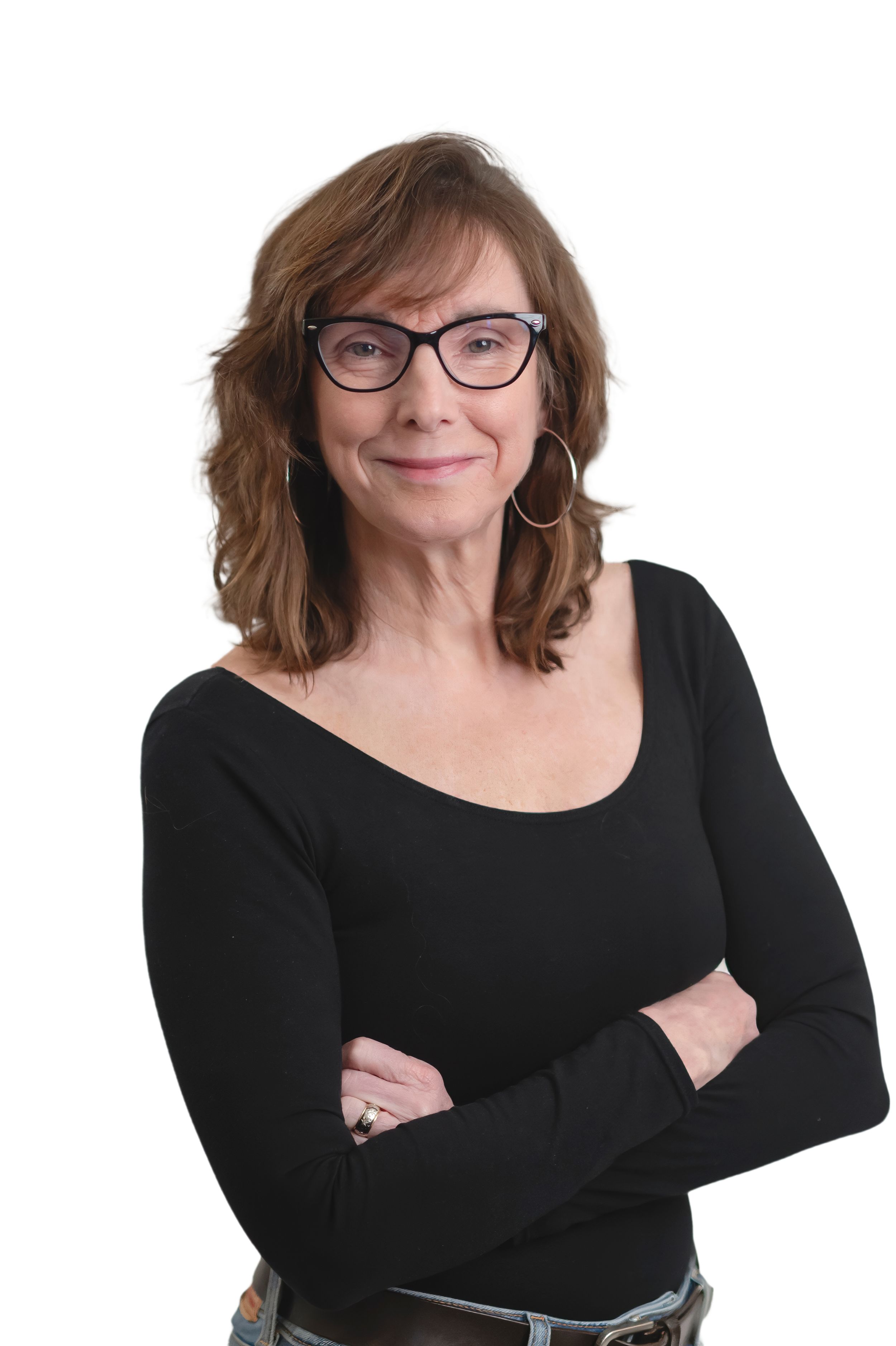 A woman with shoulder-length light brown hair, wearing glasses, hoop earrings, and a black long-sleeve shirt, standing with her arms crossed and smiling.